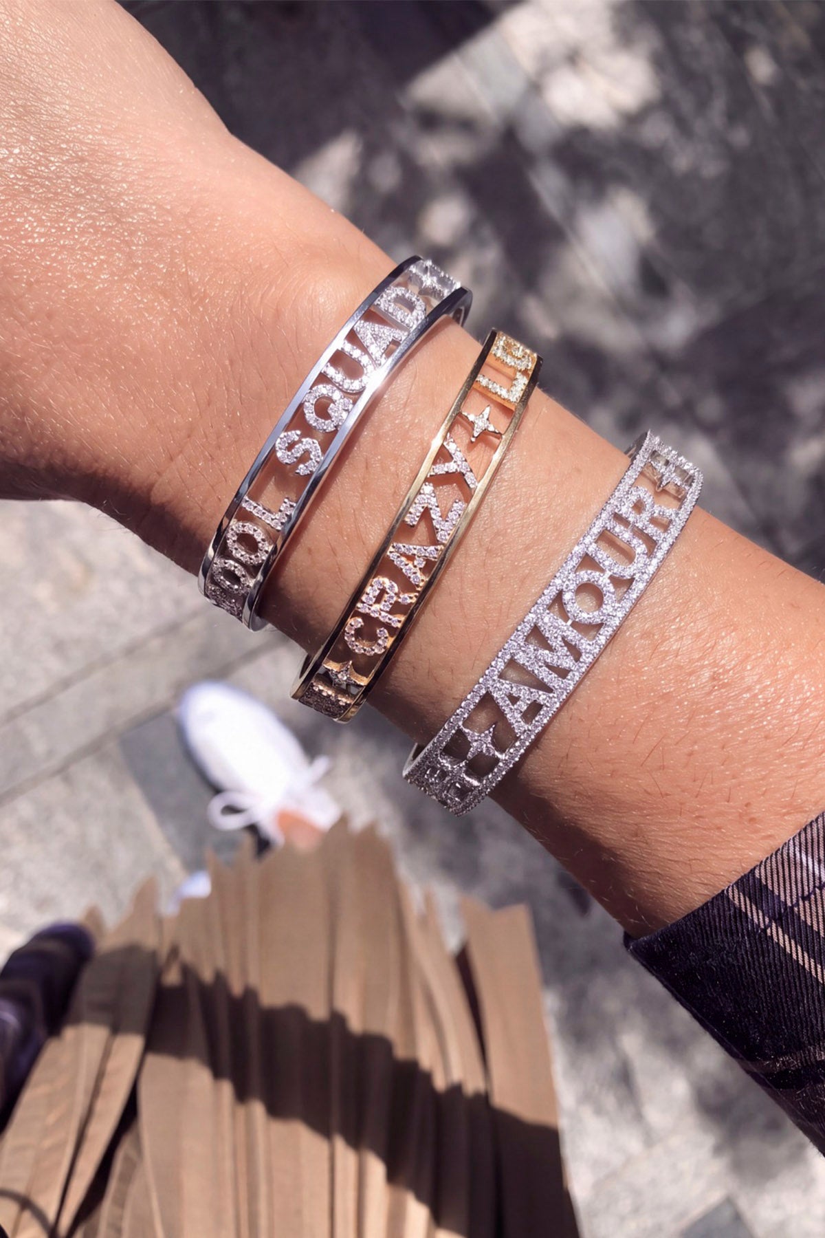 Woman wearing APM Monaco bangles, a stacked statement of shimmering words and sunlit charm.
