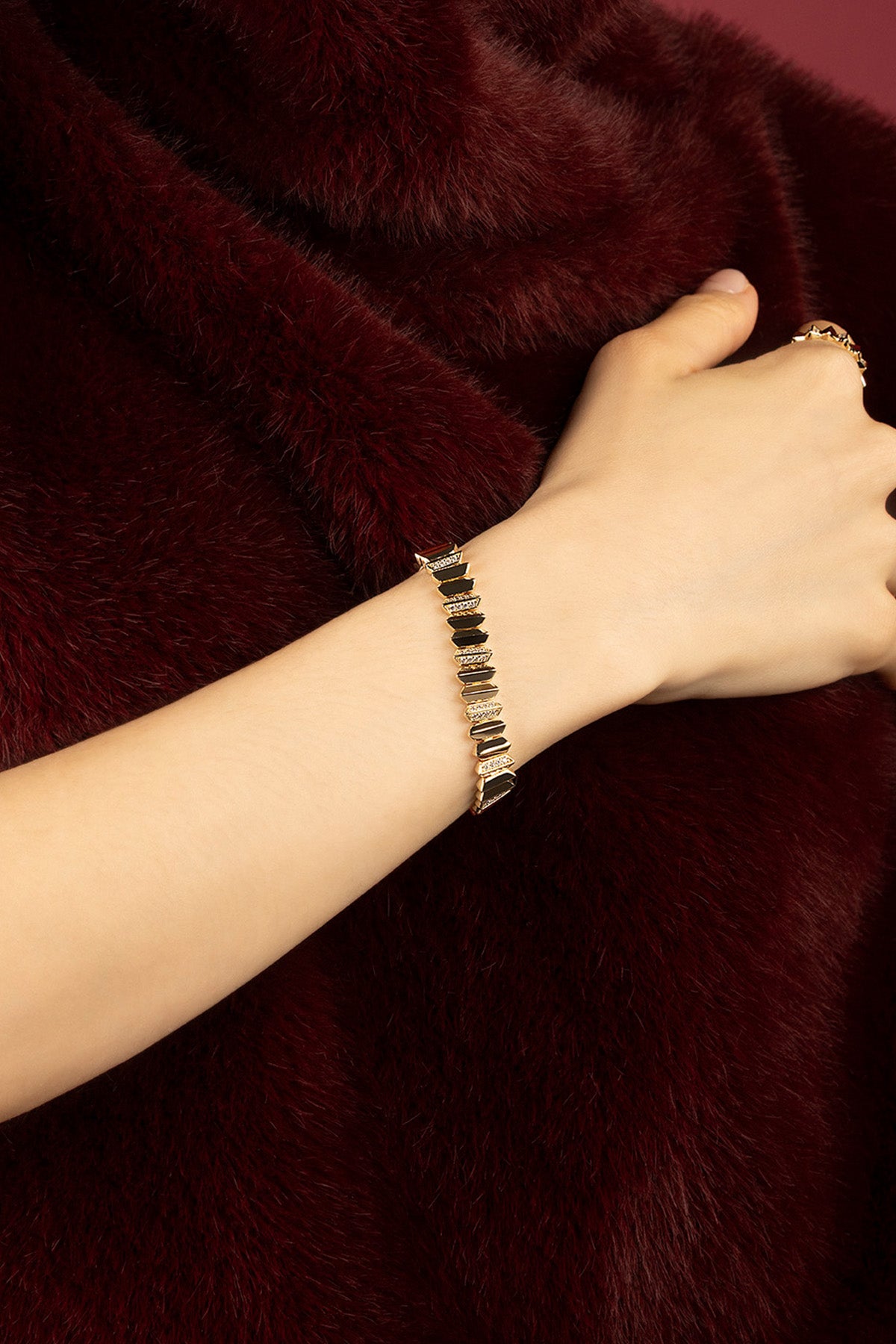 Woman wearing APM bracelet, bold geometry meets velvet allure.