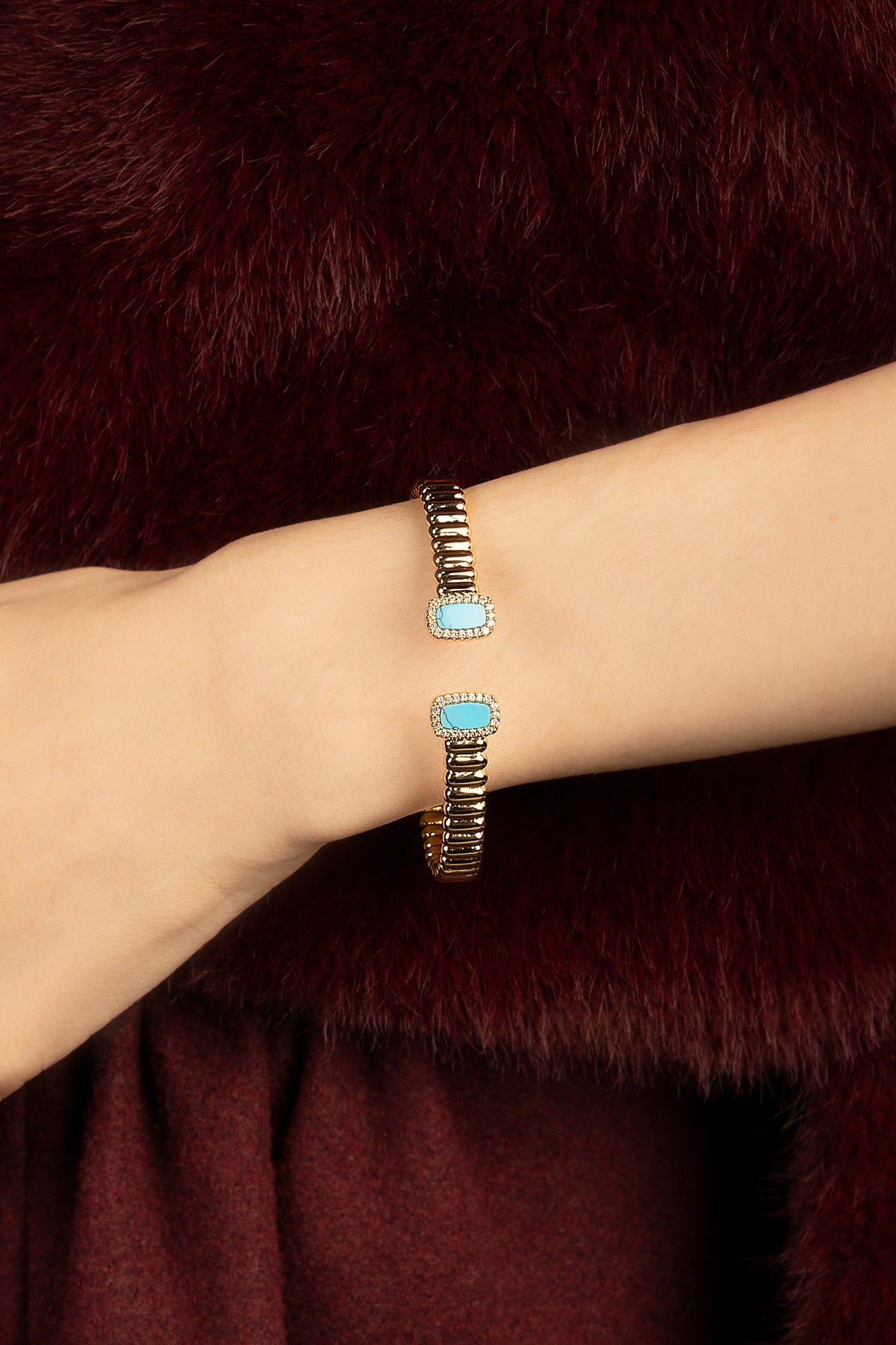 Woman wearing APM cuff bracelet, turquoise accents on golden ridges, quietly luxurious.