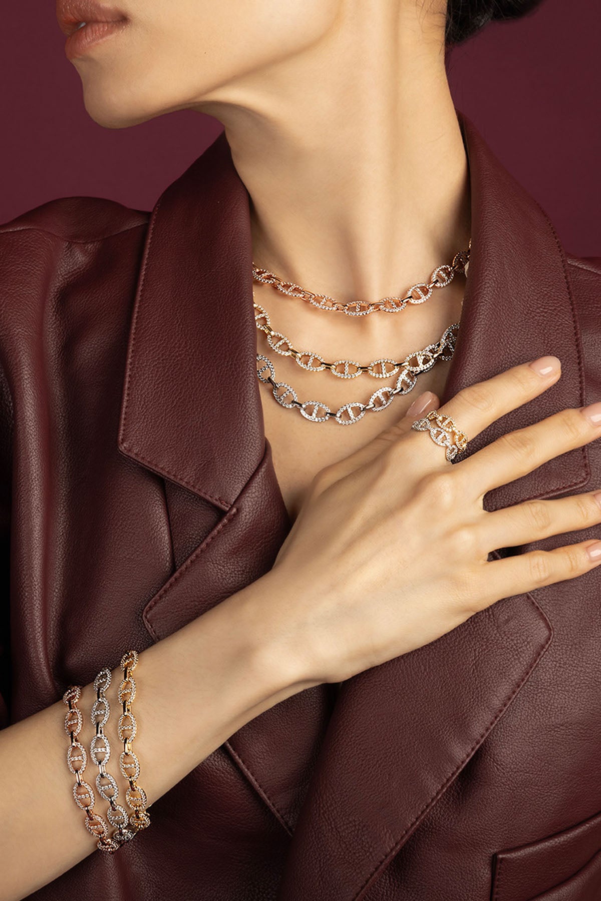 Woman wearing APM Monaco chain necklaces, bracelets and ring, layered boldness in warm colors.