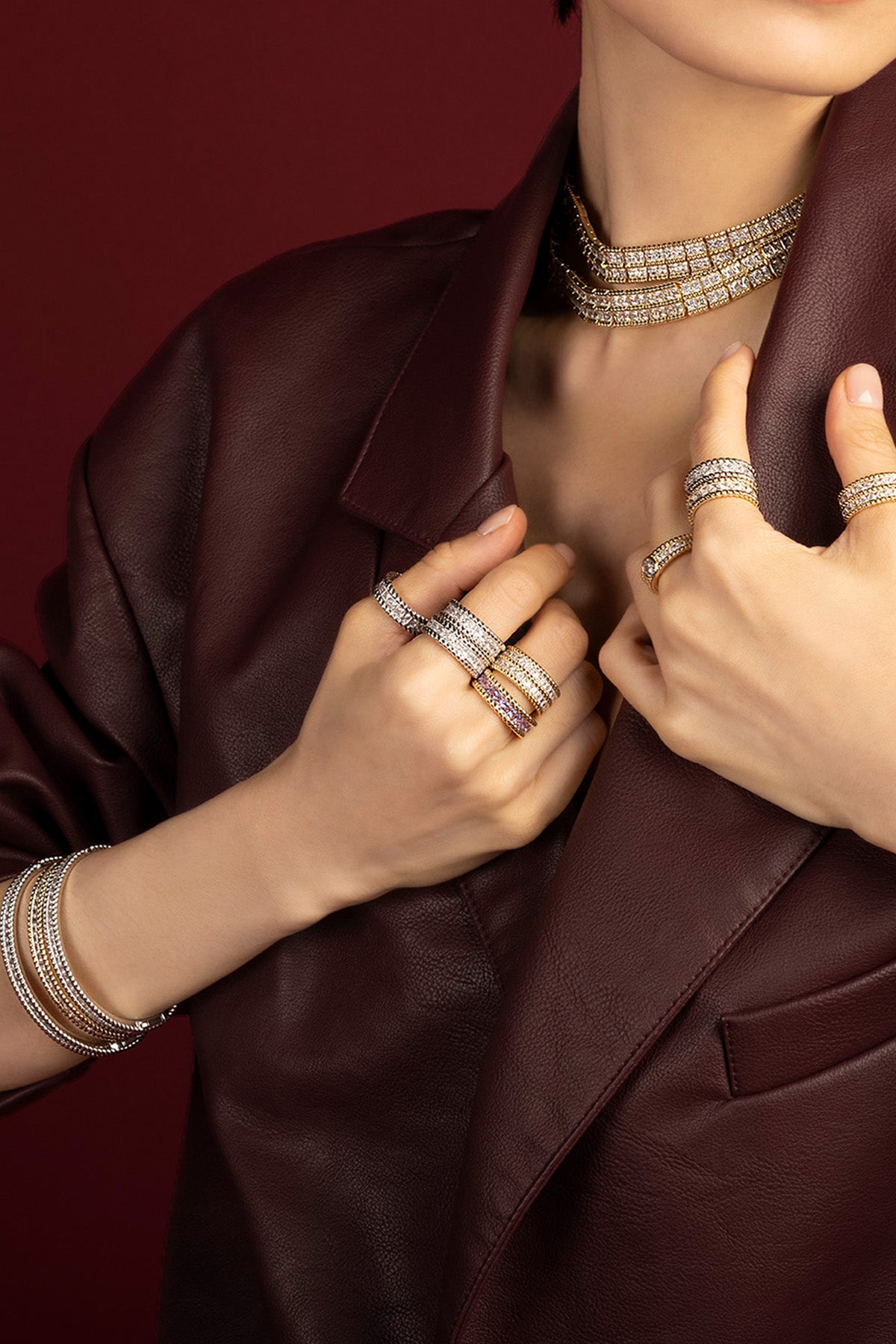 Woman wearing APM Monaco layered jewelry set, bold sparkle meets burgundy leather elegance.