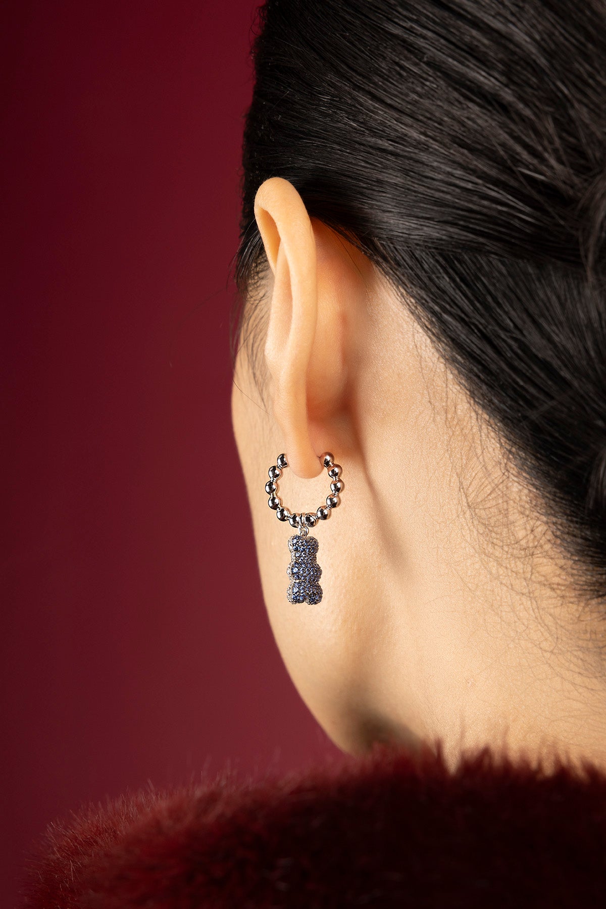 Woman wearing APM Yummy Bear hoop earrings, a playful whisper of midnight charm.