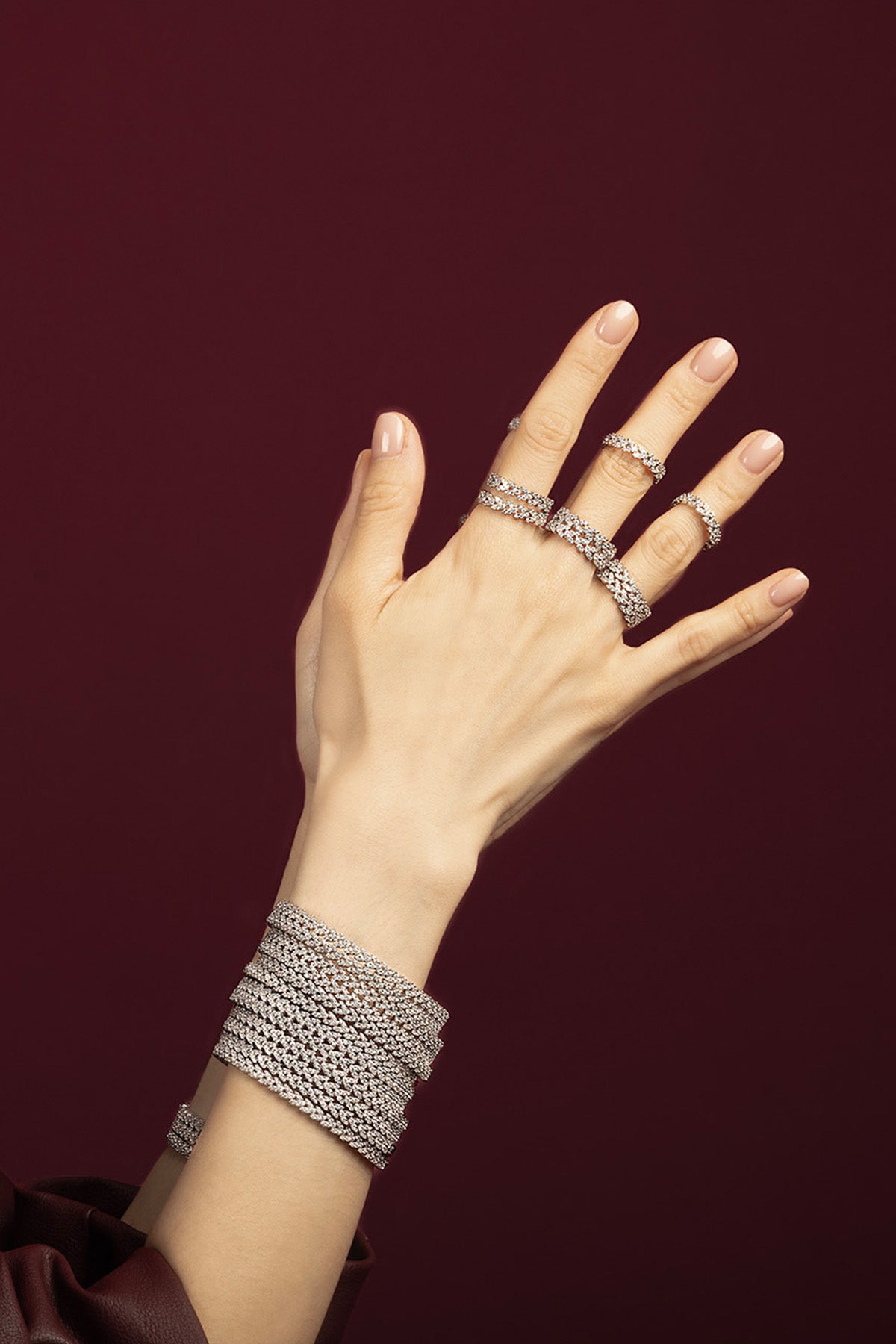 Woman wearing APM Monaco stacked bracelets and rings, a shimmering statement in rhodium finish.