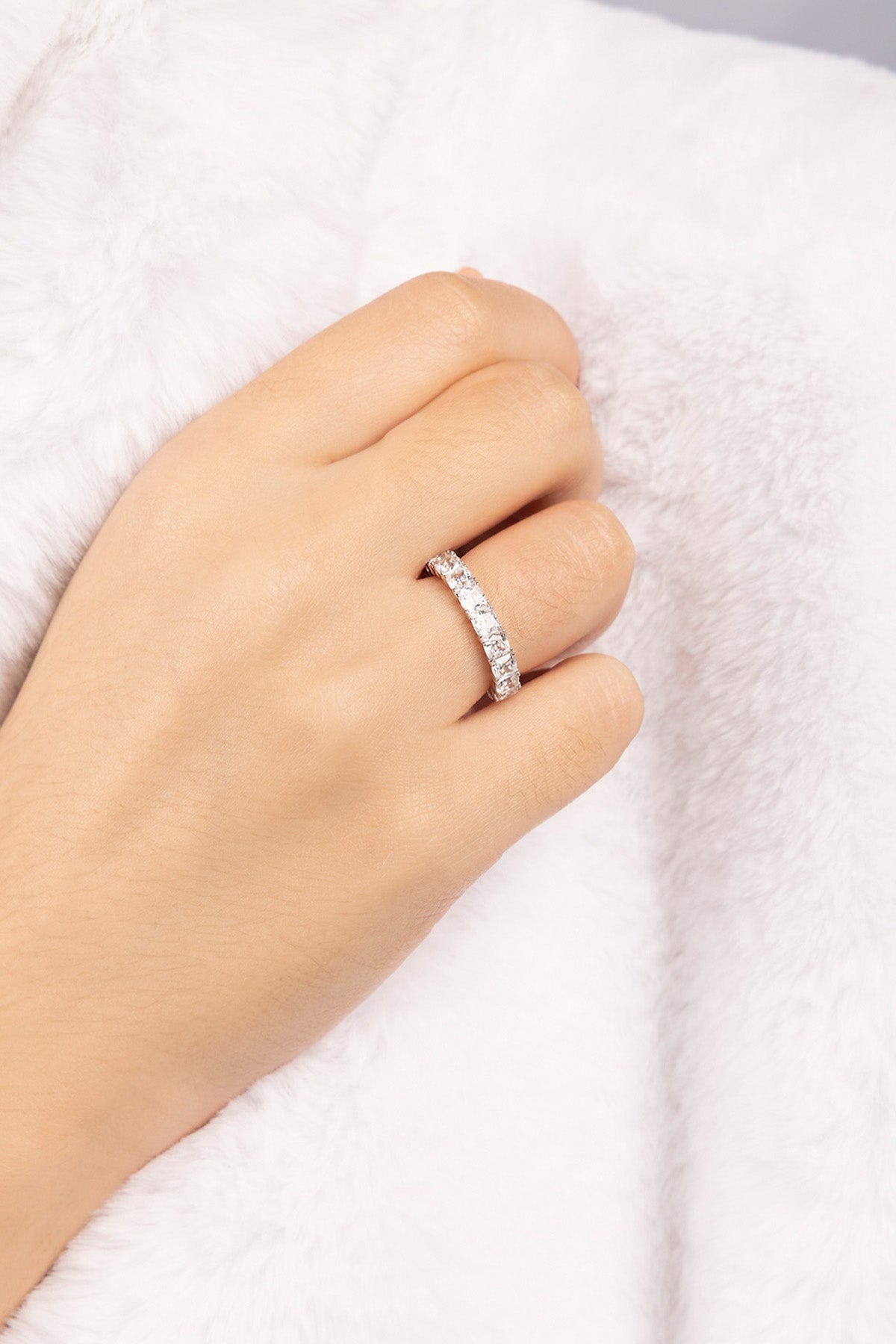 Hand wearing APM MONACO silver ring on a white background