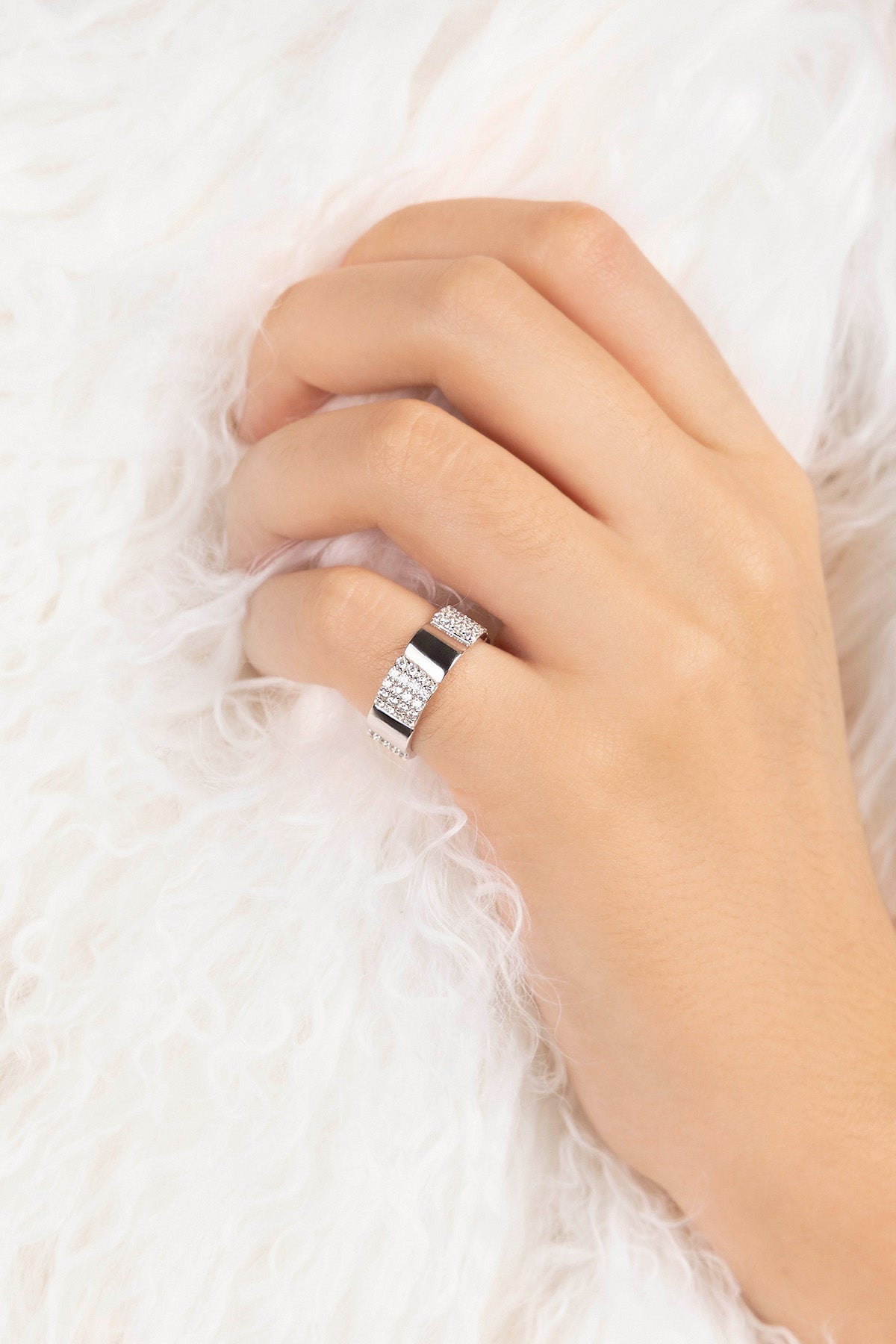 Hand wearing a silver ring on a white textured background