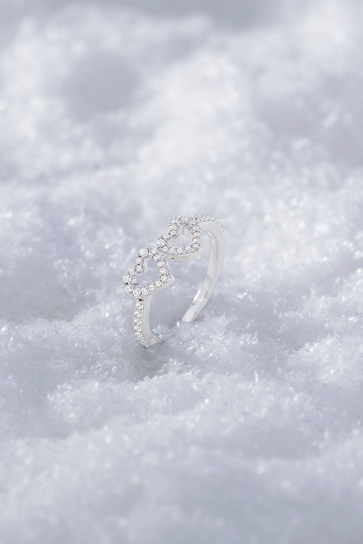 APM MONACO silver ring with heart-shaped design on a snowy background