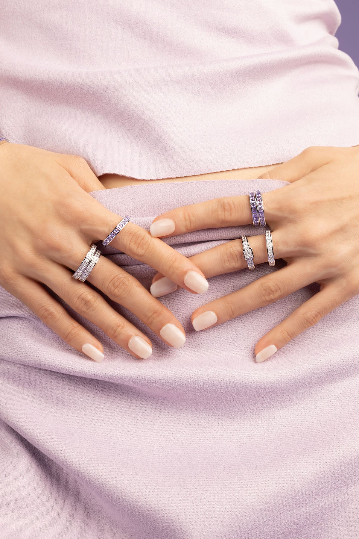 Hand wearing a white zirconia ring on a light purple background
