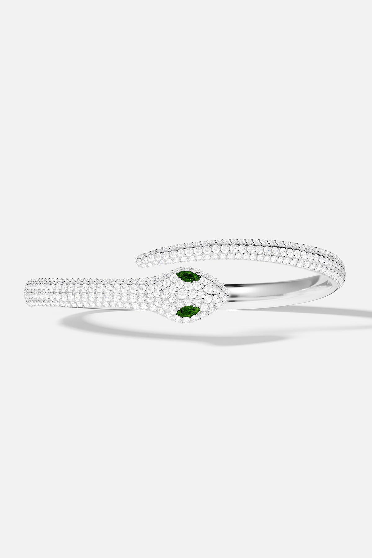 Bracelets APM Monaco, snake wrap cuff in silver-tone metal with white pavé rhinestones and green eyes.