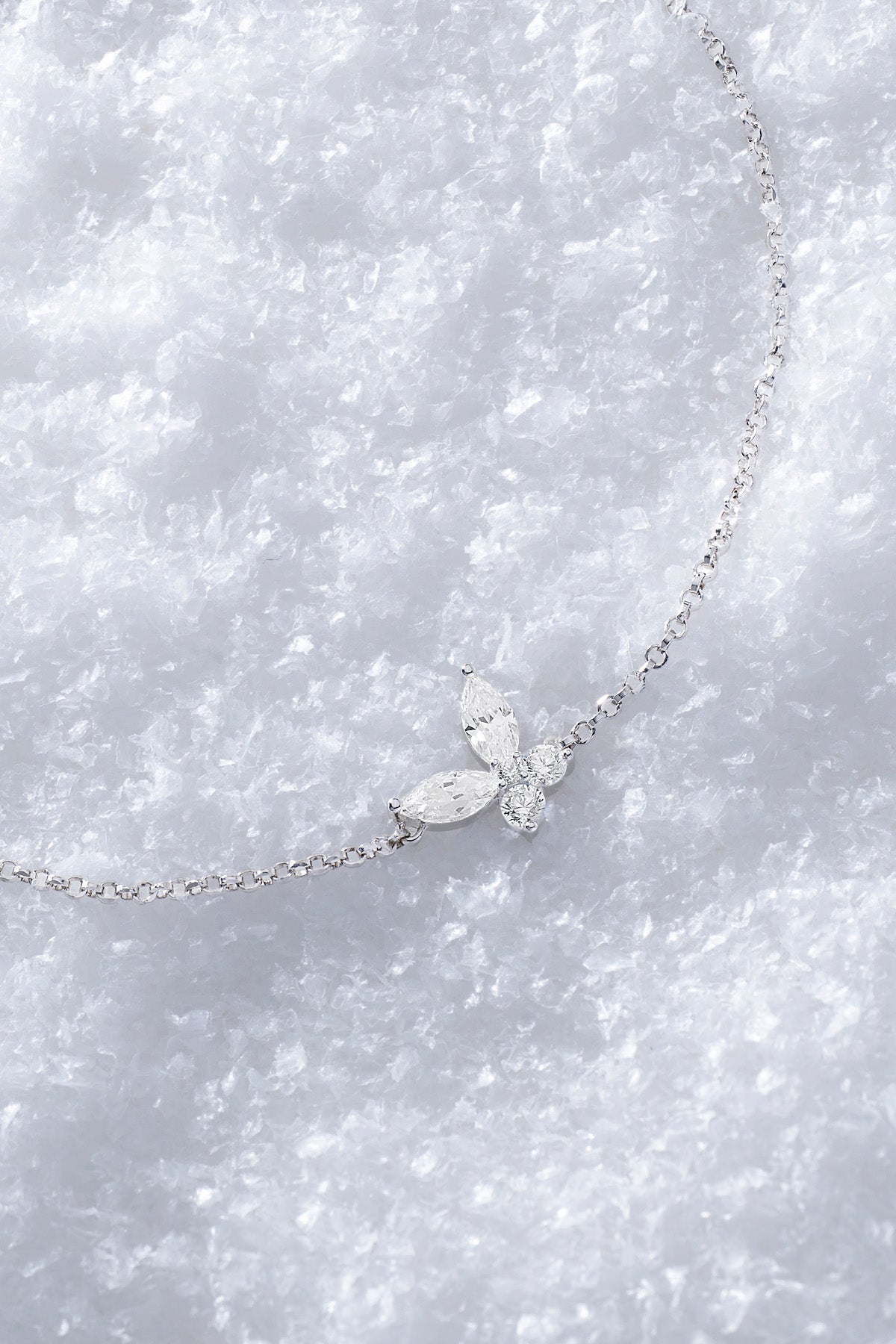 APM MONACO silver necklace with butterfly-shaped white pendant on a snowy surface