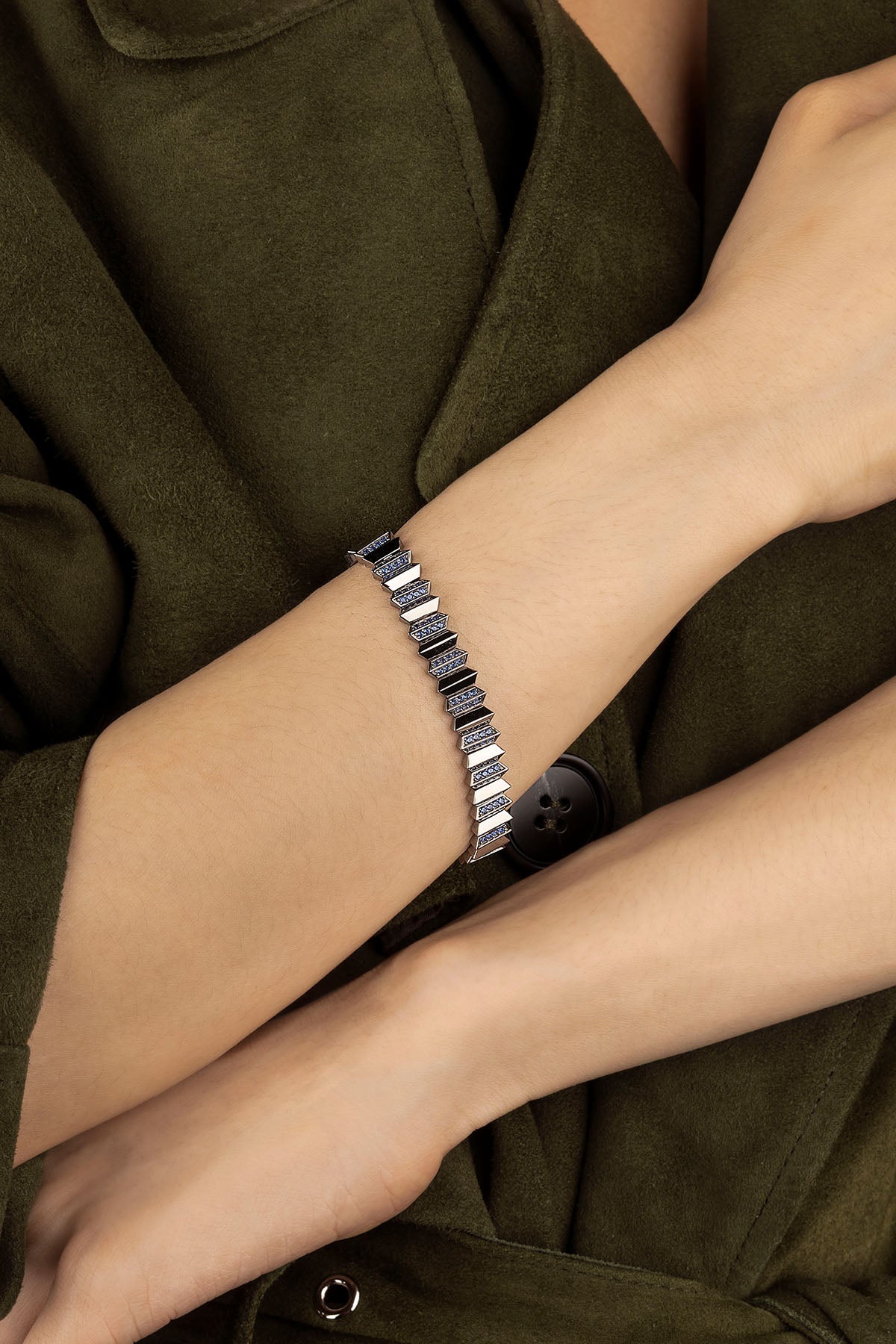 Silver bracelet on a person's wrist with a dark green coat