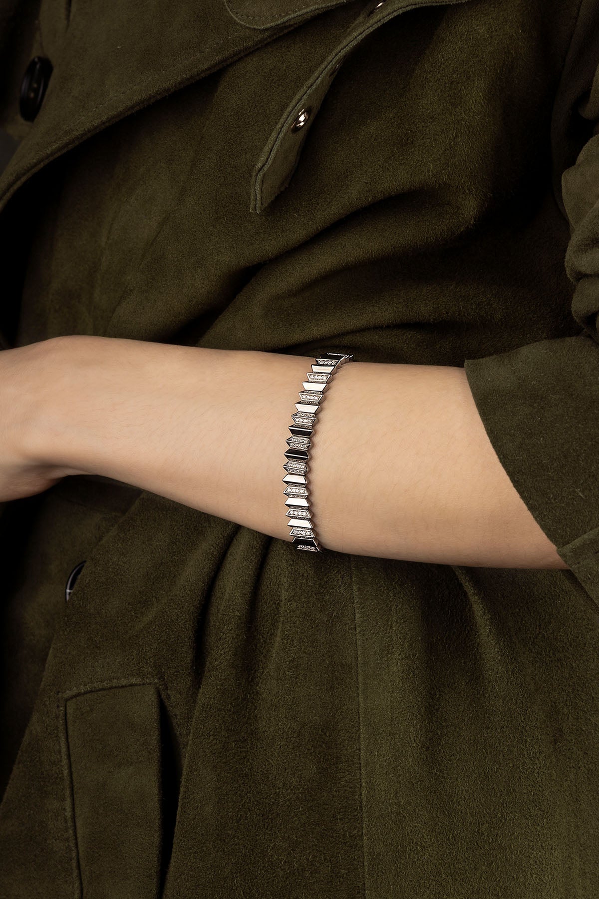 Model wearing a bracelet on an arm with a dark green jacket