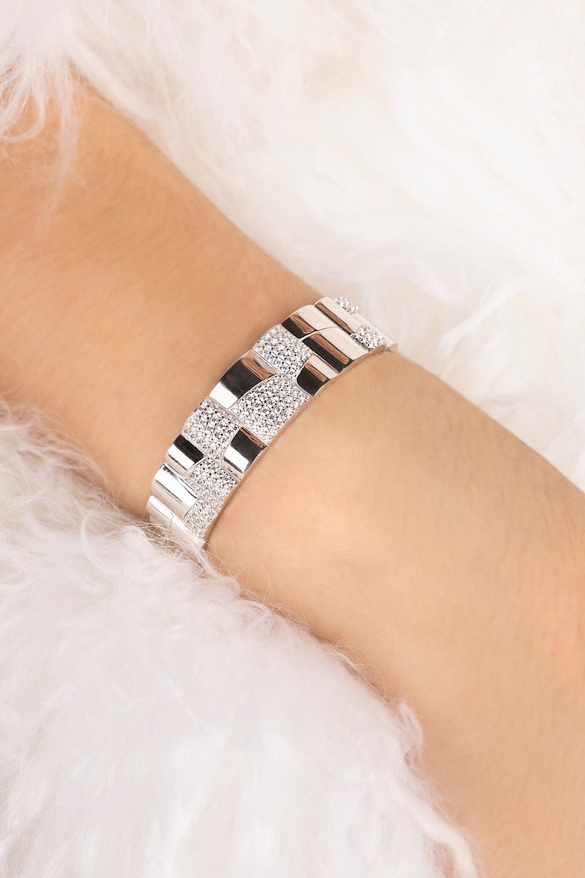 Silver bracelet on a person's wrist with a white fur background