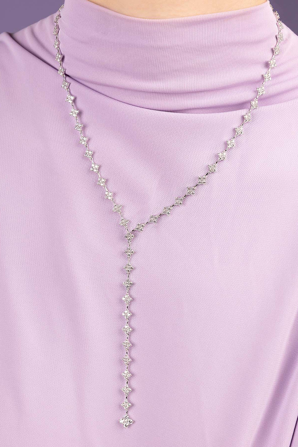 APM Monaco Y-Drop Spark Adjustable necklace wearing a light purple top against a purple background