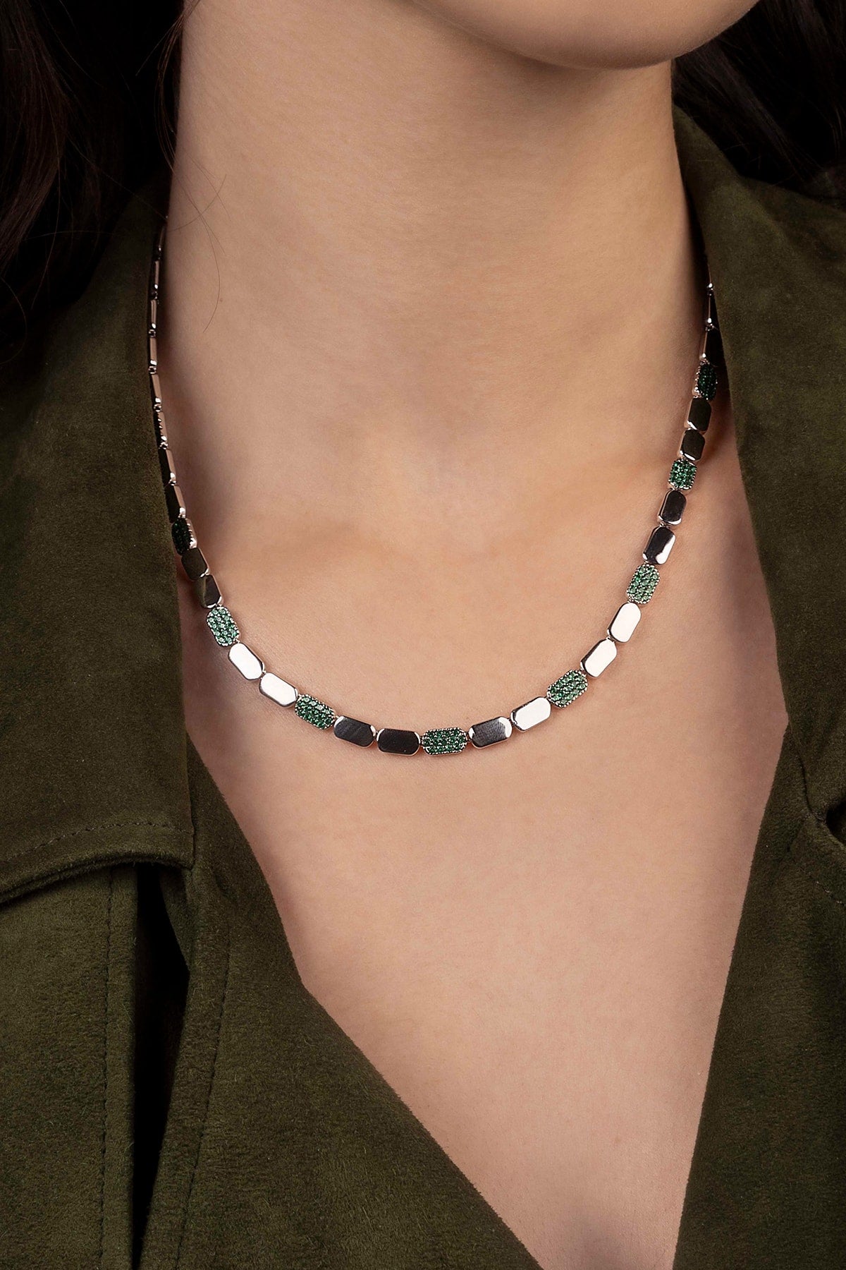 Silver necklace worn by a model in a green outfit.