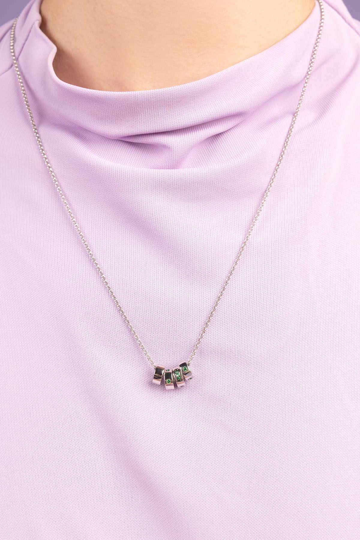 APM Monaco Green LOVE Morse Code Adjustable necklace wearing a light purple top against a purple background