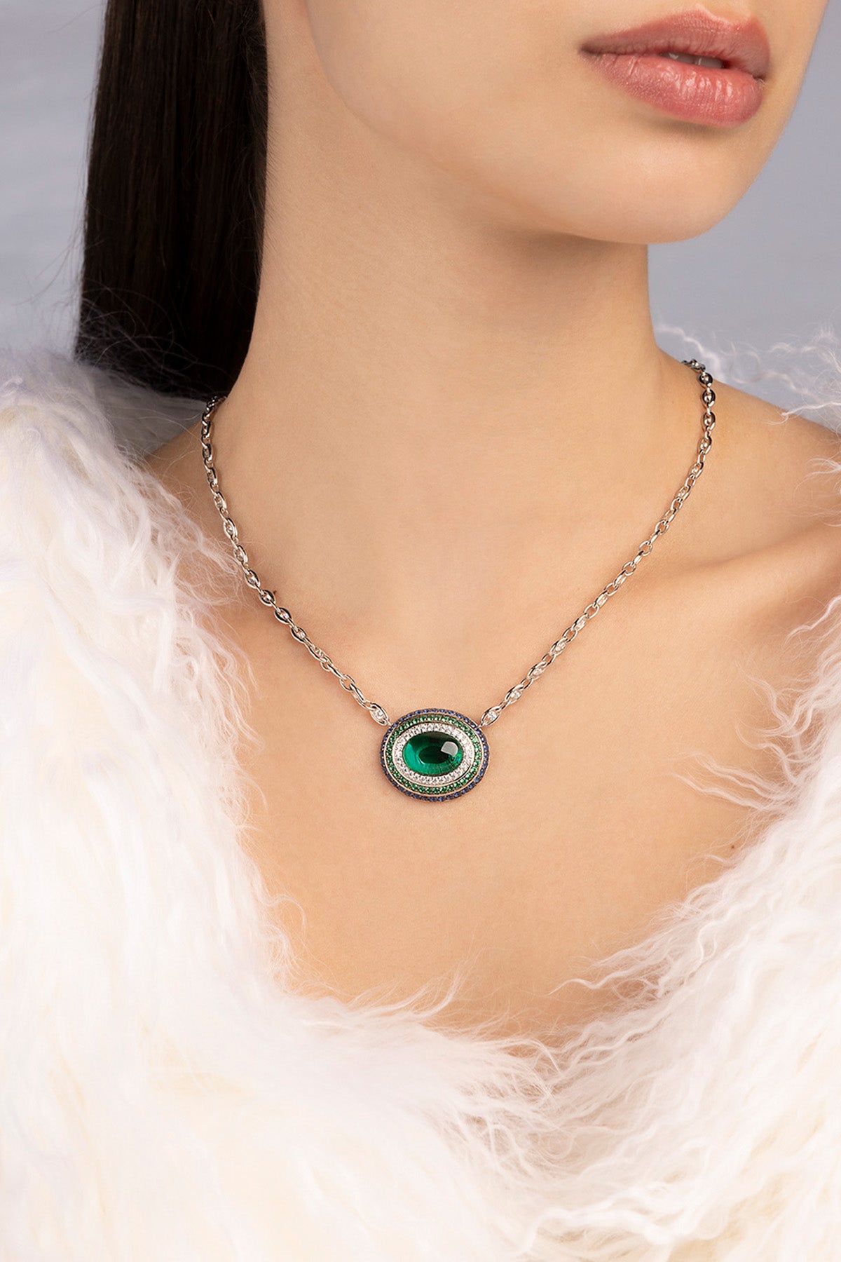 Necklace with a green pendant worn by a person against a neutral background