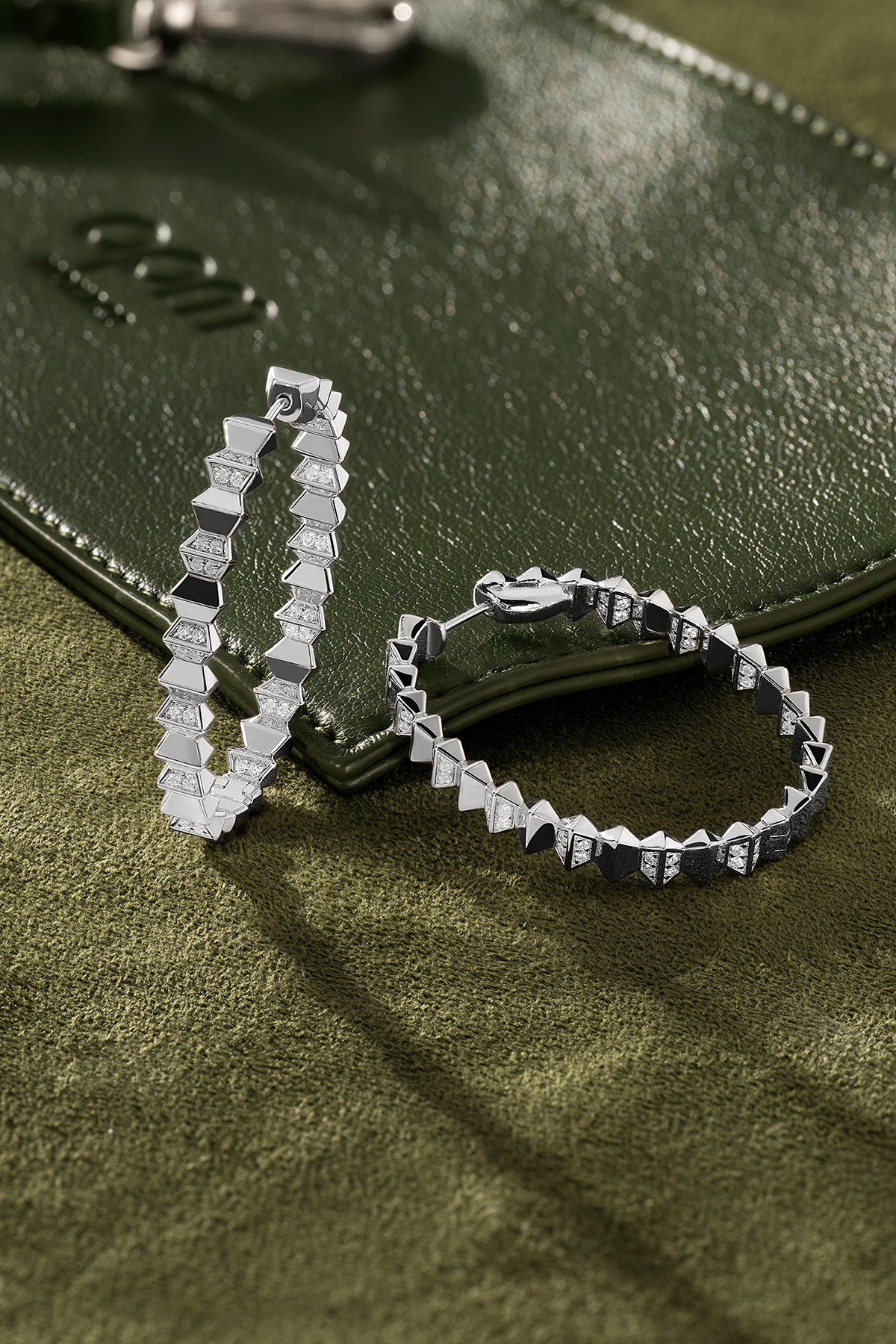 Silver hoop earrings on a green textured surface