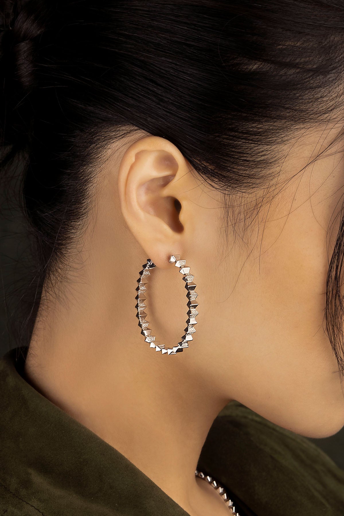 Close-up of an ear wearing a hoop earring with a dark background
