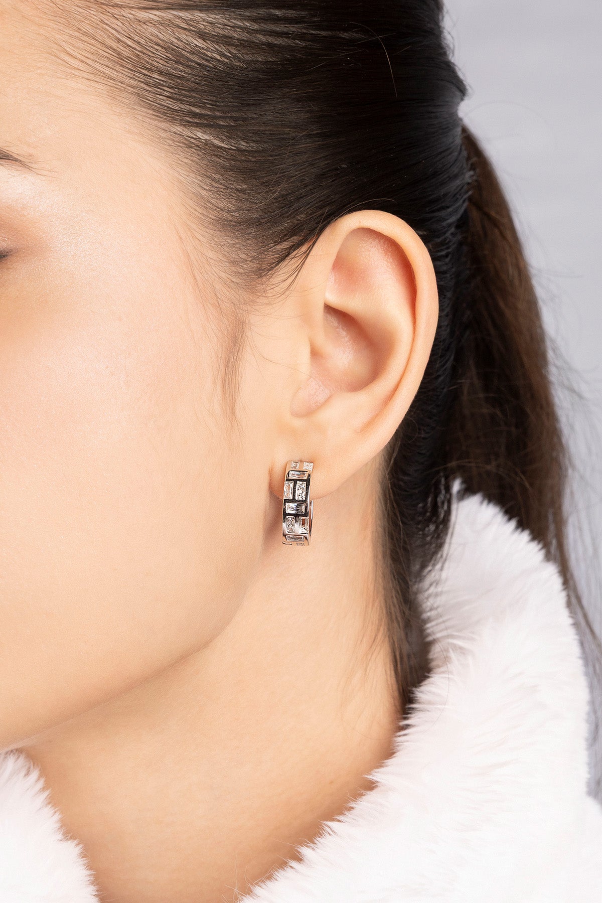 Close-up of APM MONACO labyrinth hoop earring worn by a model with a neutral background
