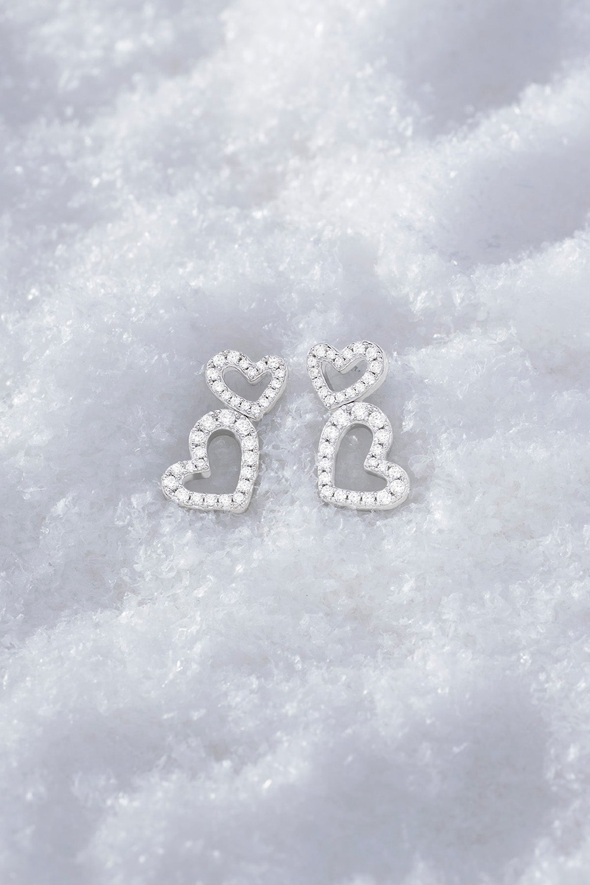 APM MONACO heart earrings in silver on soft snowy surface