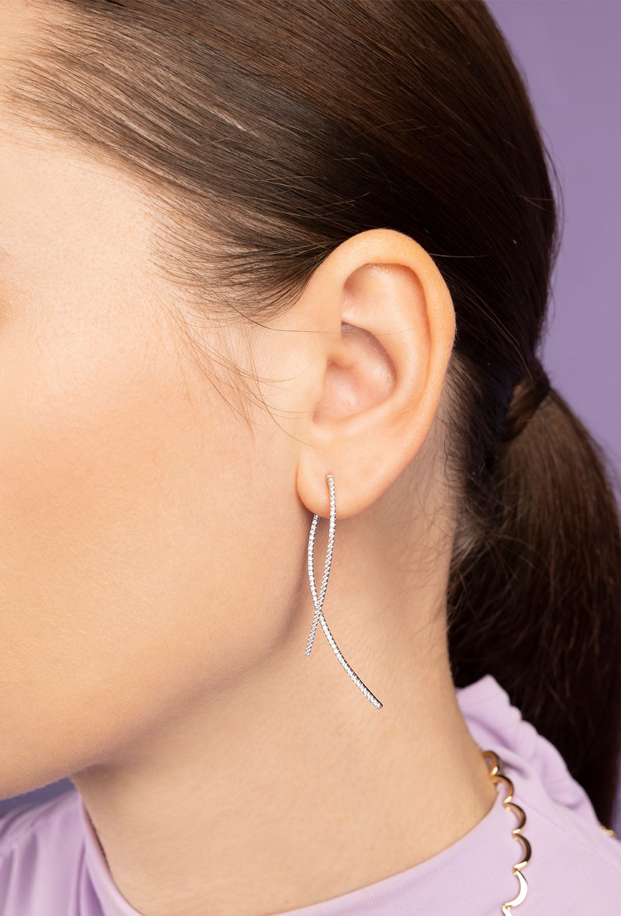 Close-up of a person wearing APM MONACO silver hoop earrings with a blurred background