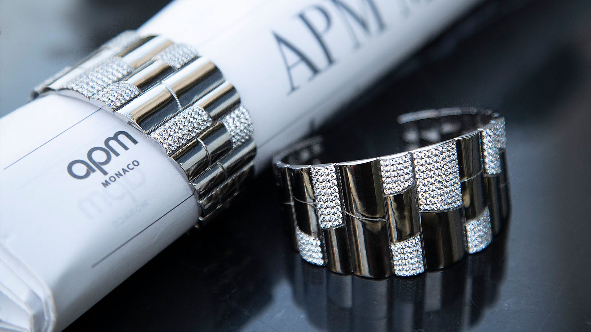 Silver APM Monaco Automne Pave Bangle on a dark surface