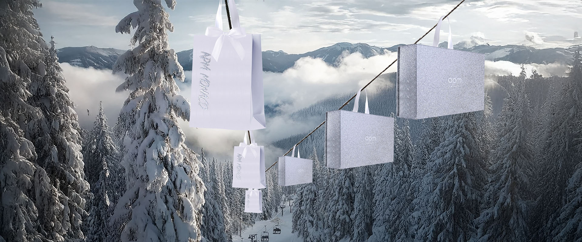 White shopping bags with APM MONACO logo hanging against a snowy mountain landscape