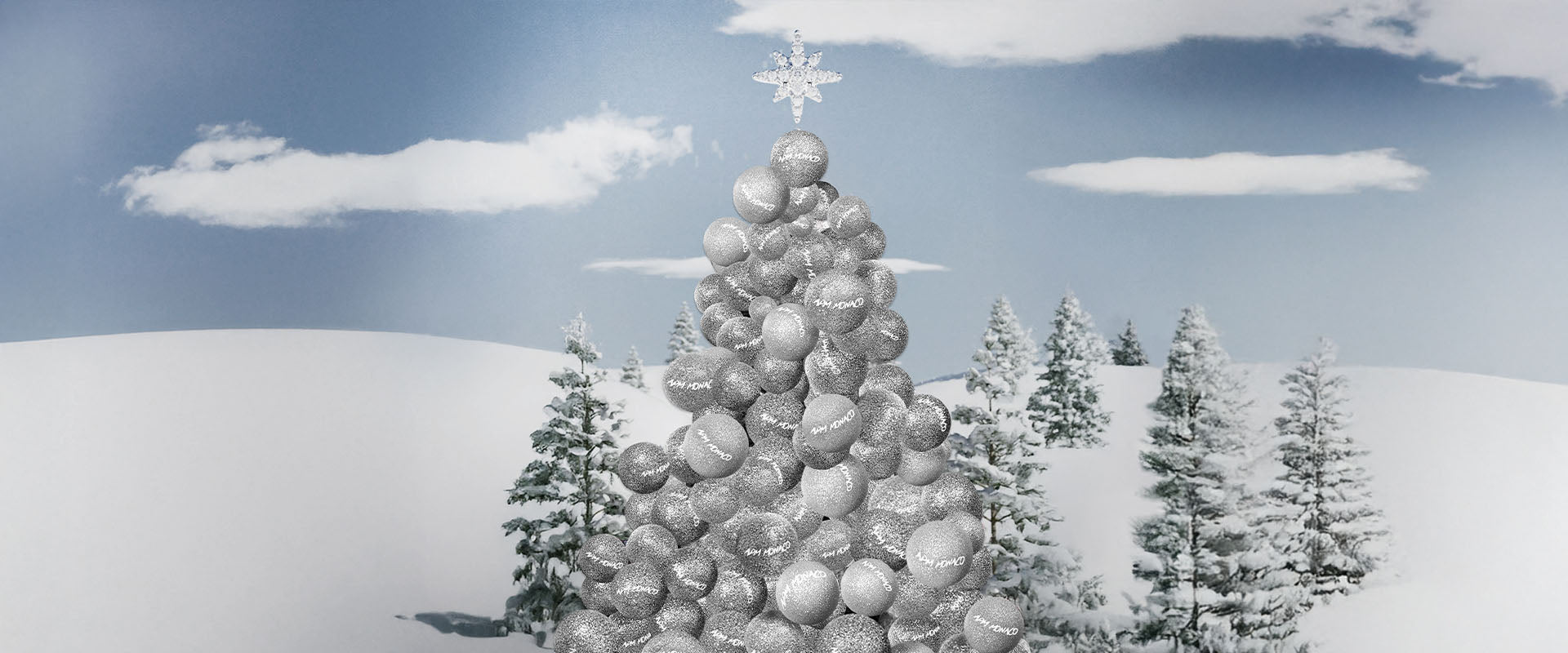 Decorative Christmas tree made of silver ornaments with APM MONACO logo against a snowy landscape with trees.