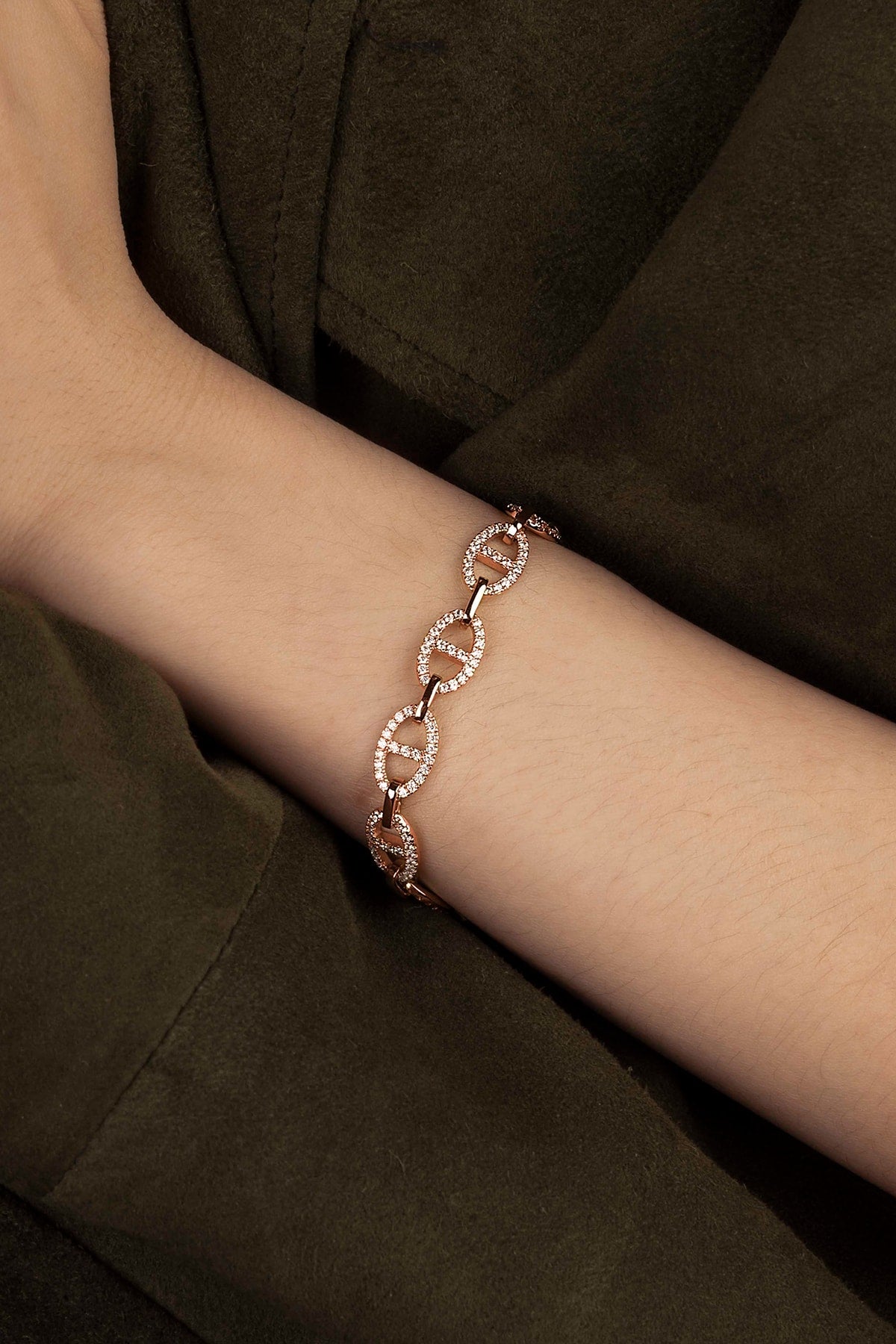 Rose gold bracelet on a wrist against a dark background
