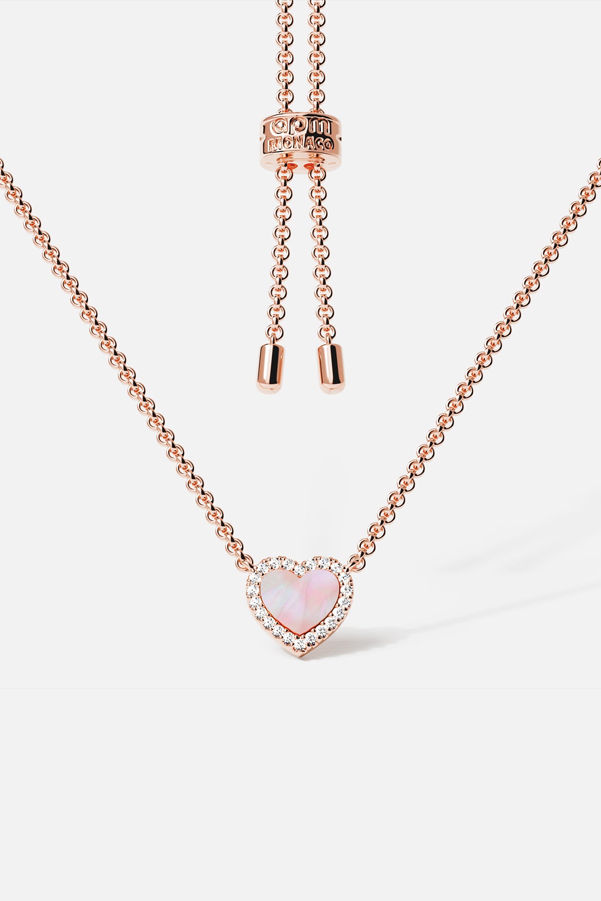 Necklaces APM Monaco, rose gold tone adjustable chain with a pink nacre (mother-of-pearl) heart pendant surrounded by crystal pavé.