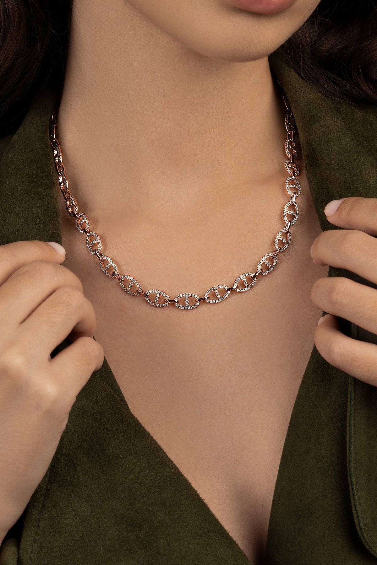 Rose gold chain necklace being worn by a person with a green garment.