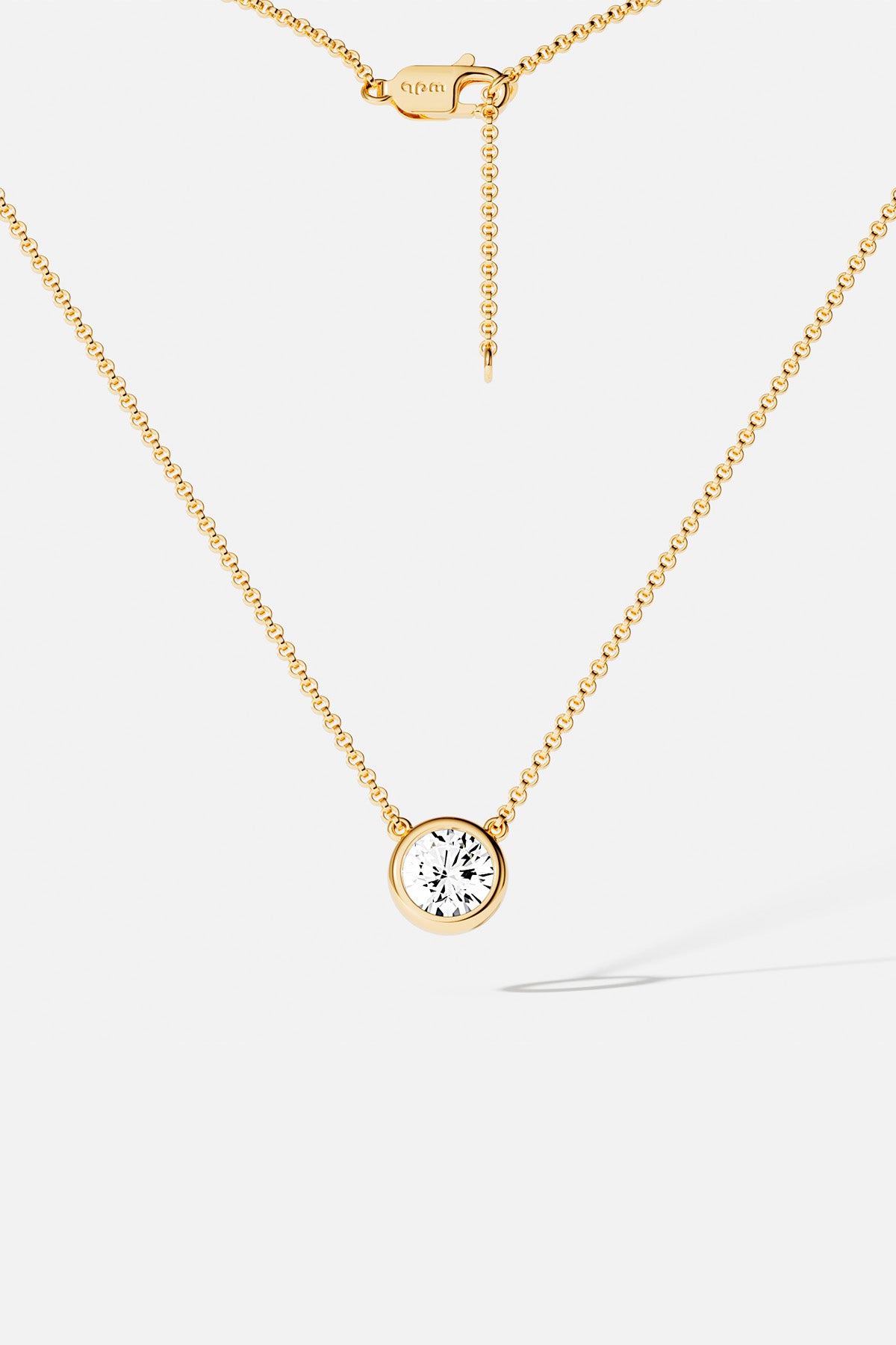 Necklaces APM Monaco, yellow gold chain with a single round clear gemstone pendant.