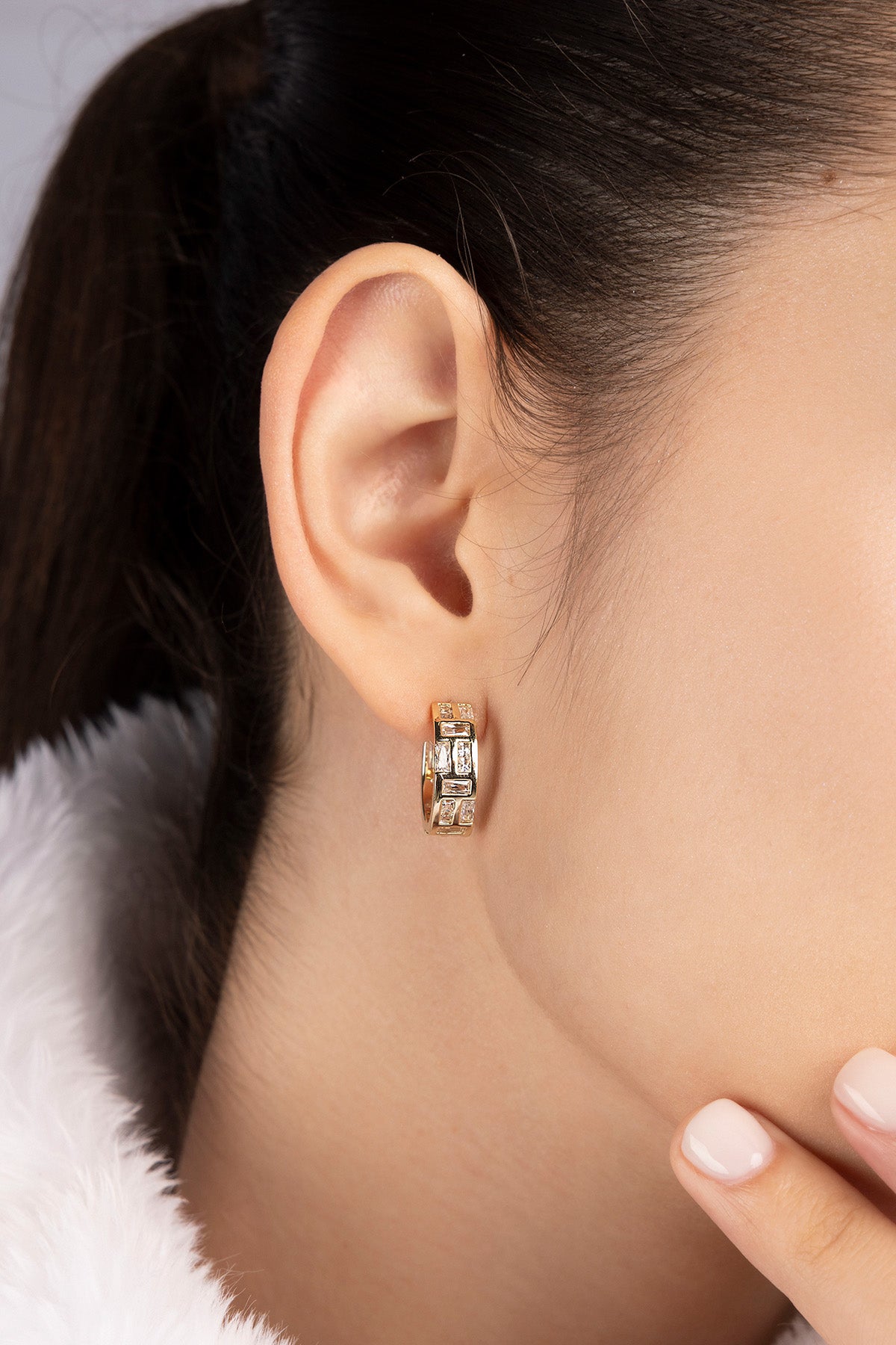 Close-up of a model wearing APM MONACO labyrinth hoop earring in yellow gold