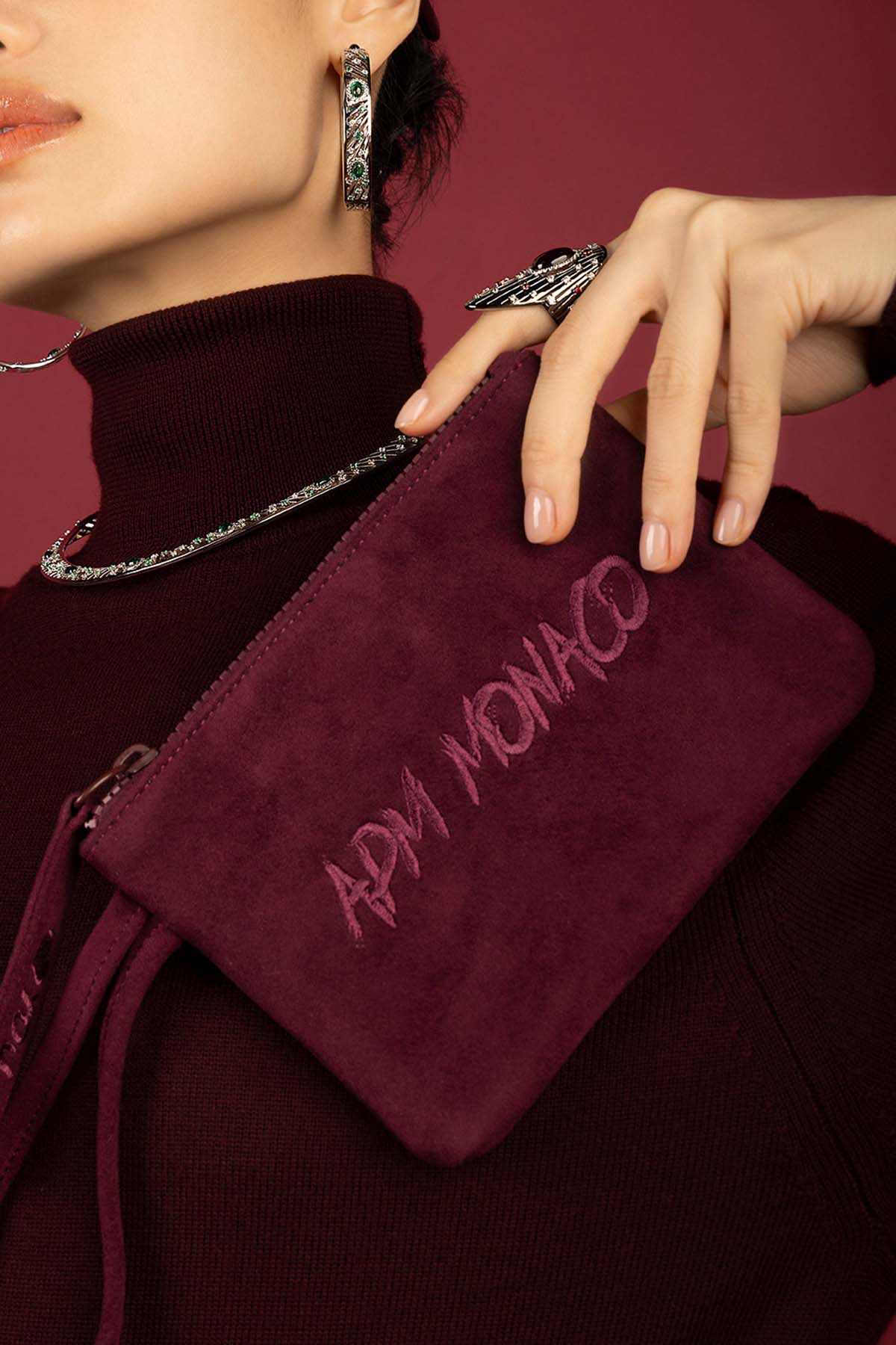 Woman wearing APM hoop earrings, necklace and ring, a bold burgundy statement.