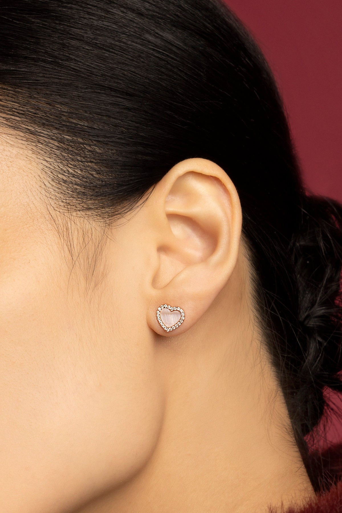 Woman wearing APM heart stud earrings, a tender glow of romance.