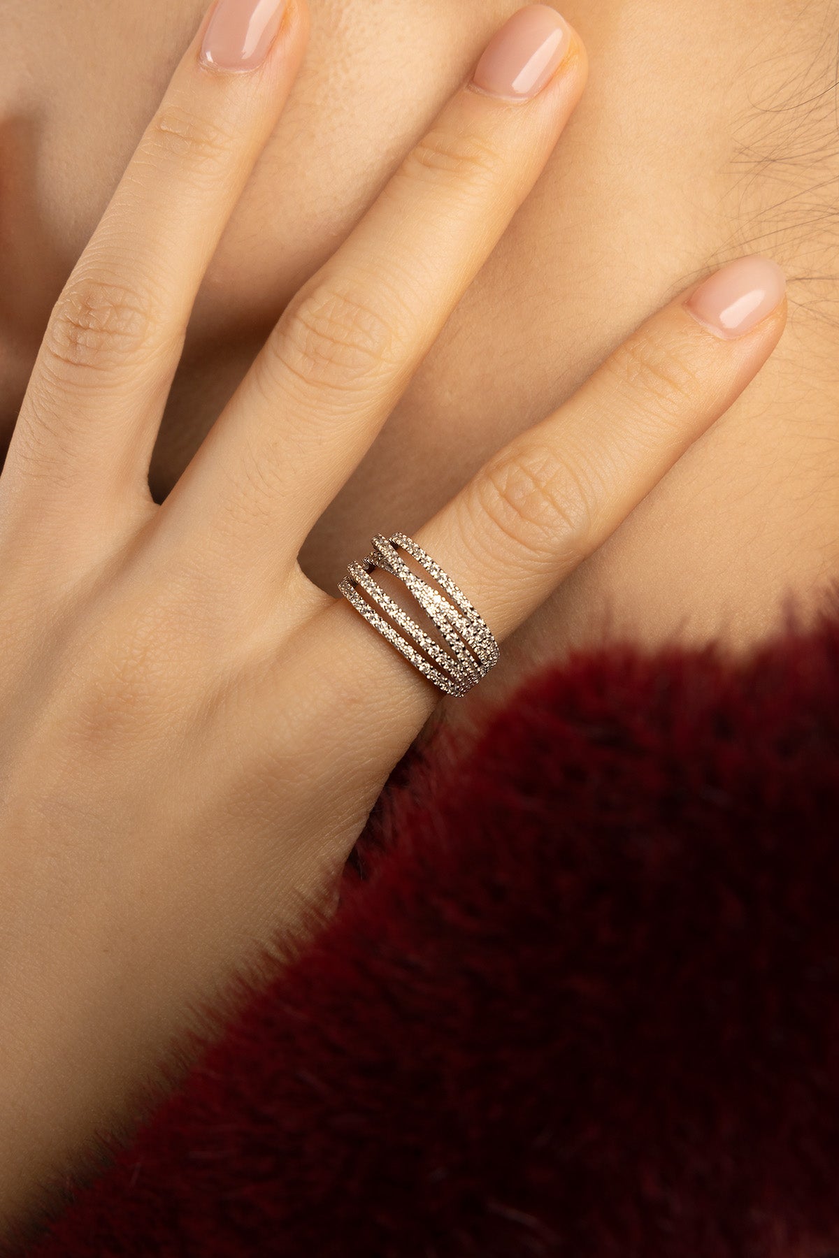 Woman wearing APM Monaco ring, sparkling layered lines in warm rose color.