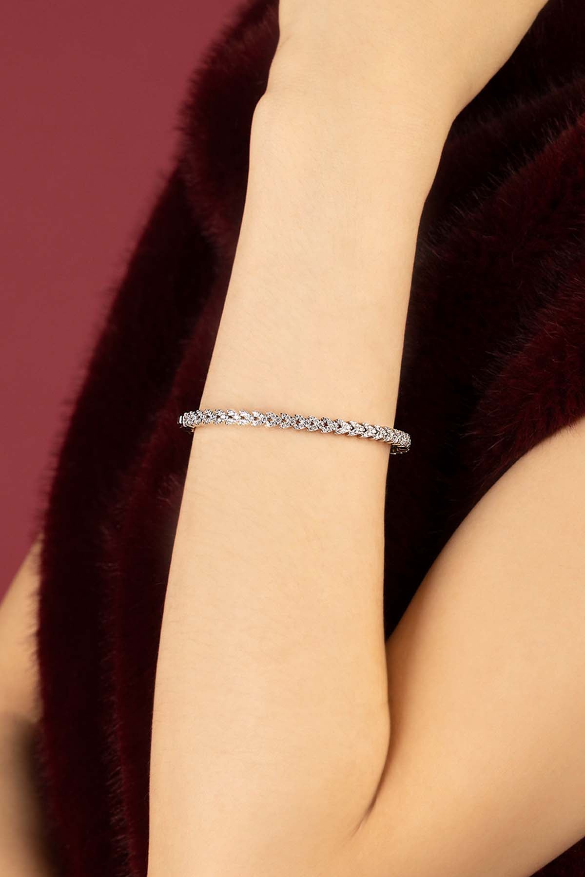 Woman wearing APM Monaco bracelet, a shimmering twist of light against velvet warmth.