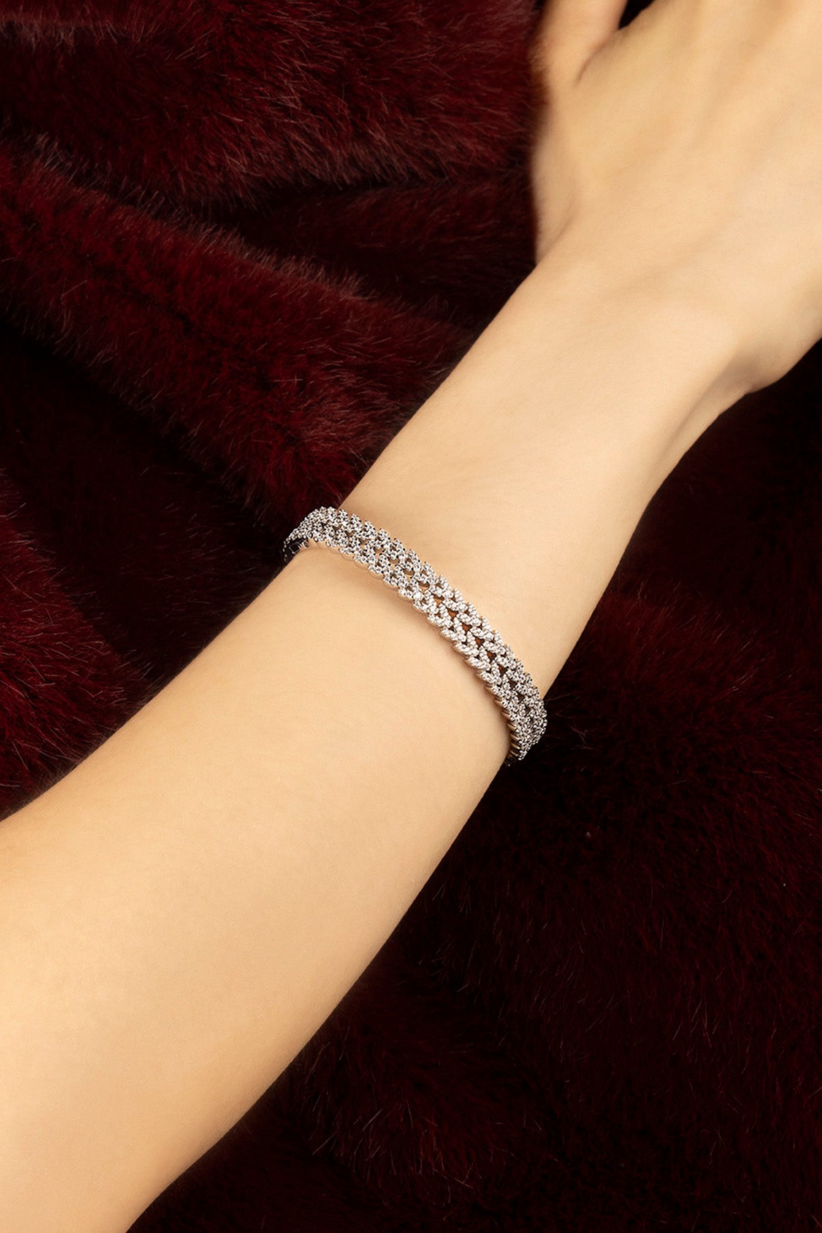 Woman wearing APM bracelet, a shimmering rhodium finish against velvet warmth.
