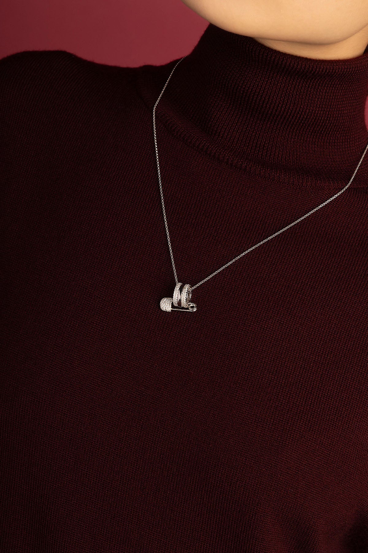 Woman wearing APM Monaco pin pendant necklace, effortless charm in rhodium finish.