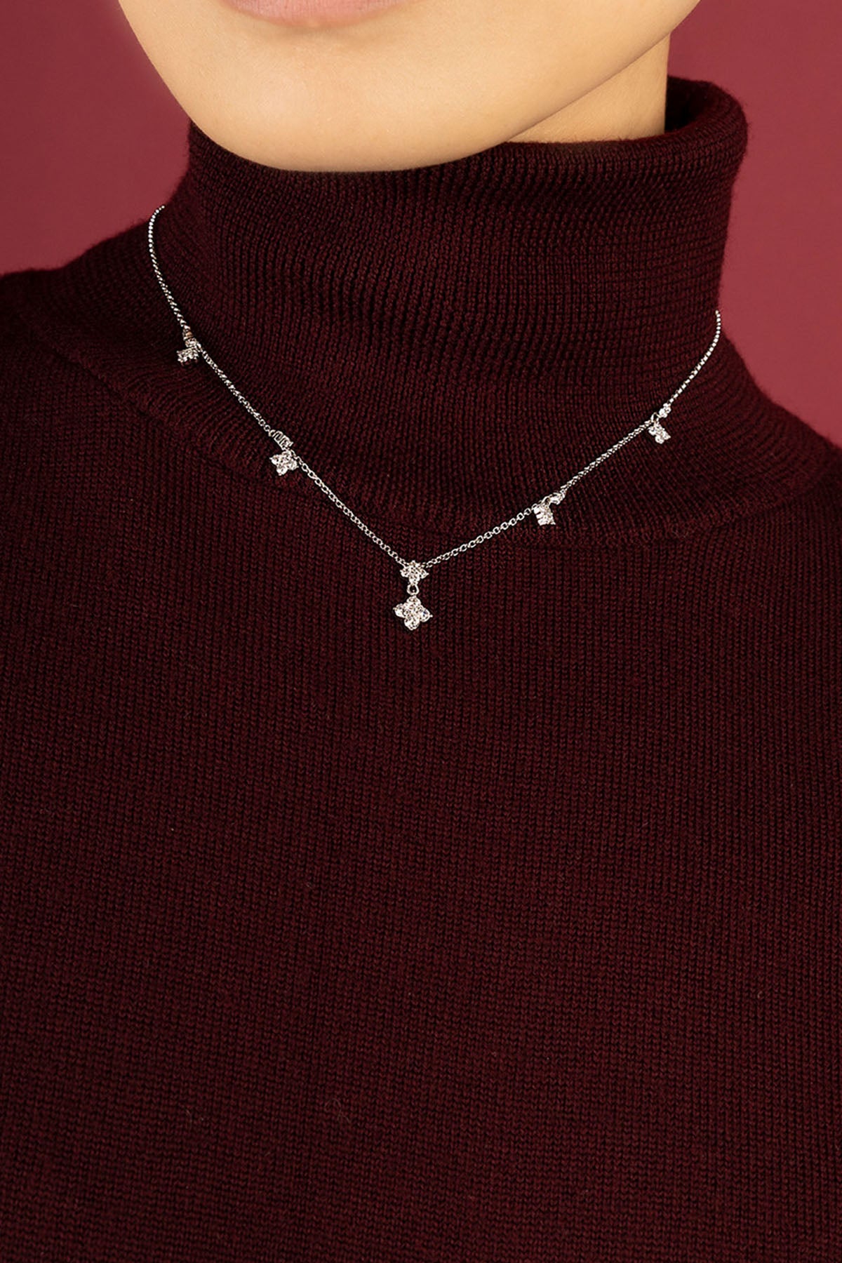 Woman wearing APM necklace, delicate charms scattered across a rhodium finish chain.
