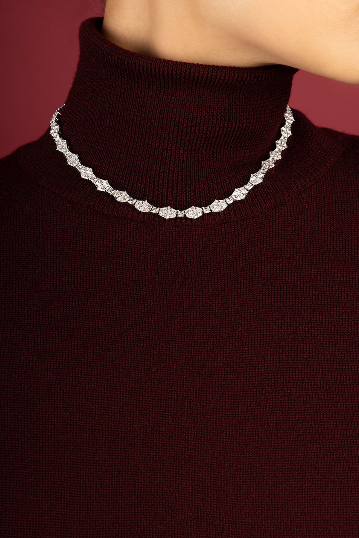 Woman wearing APM necklace, a radiant sparkle over cozy burgundy elegance.