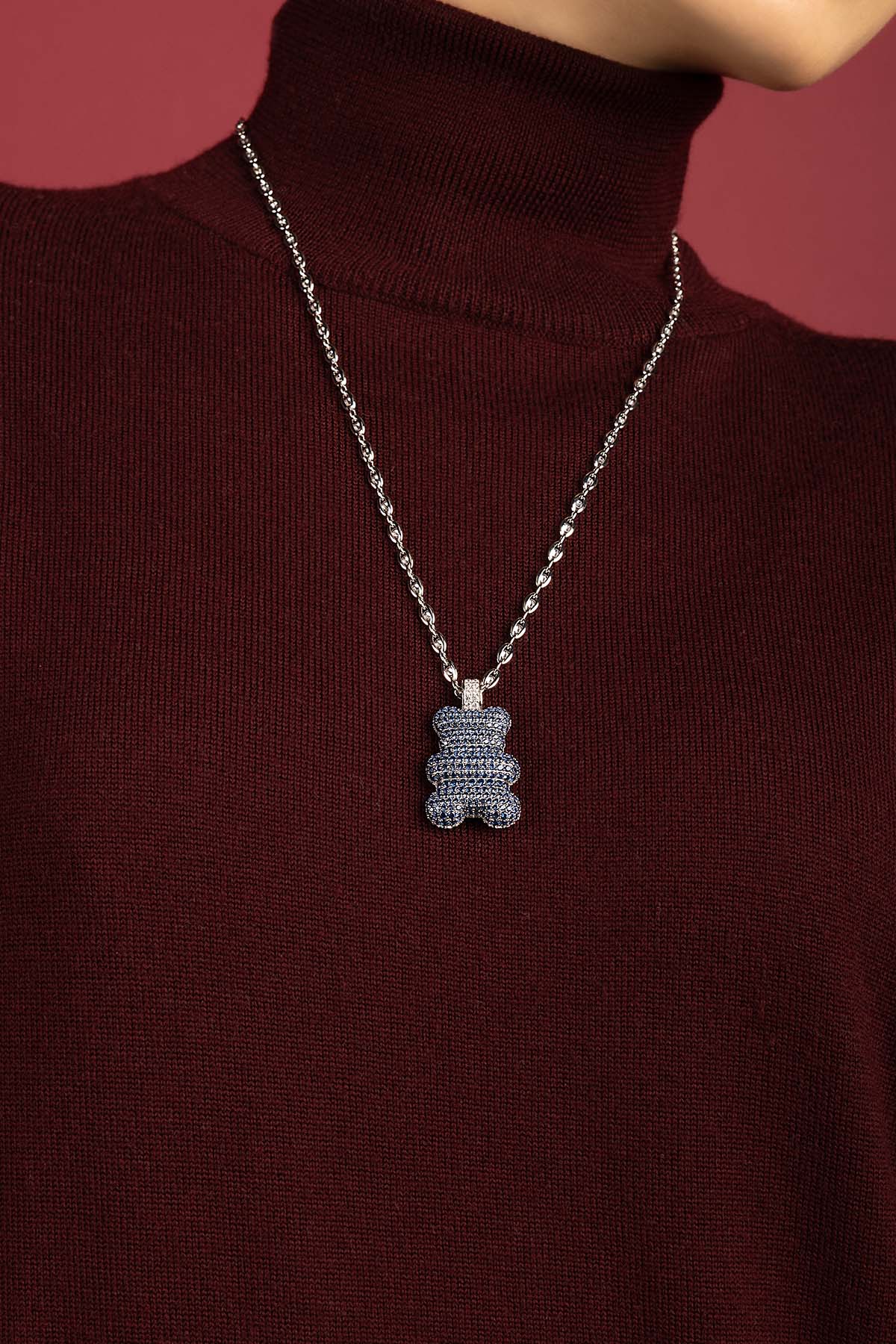 Woman wearing APM Yustli Bear Necklace, a playful charm against burgundy elegance.