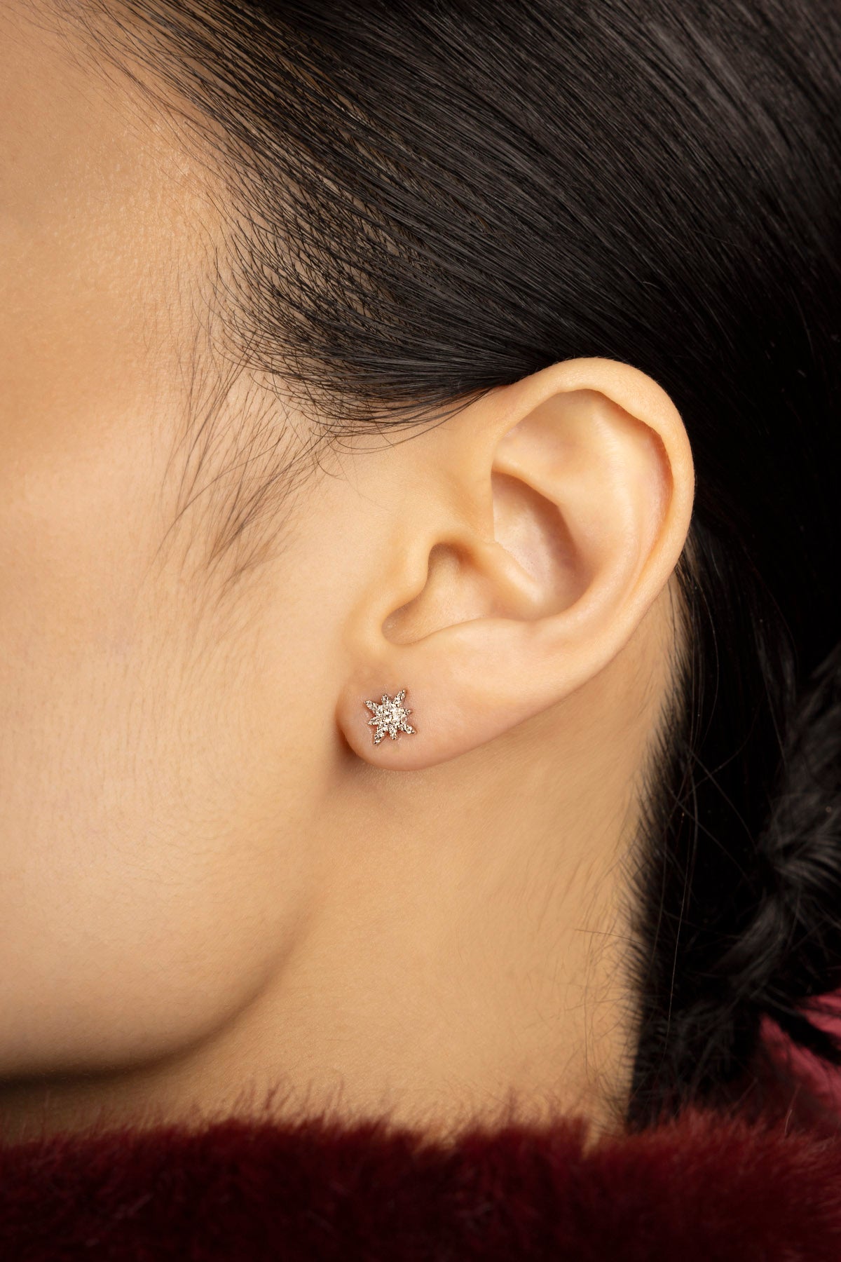 Woman wearing APM star stud earrings, a delicate spark of quiet elegance.