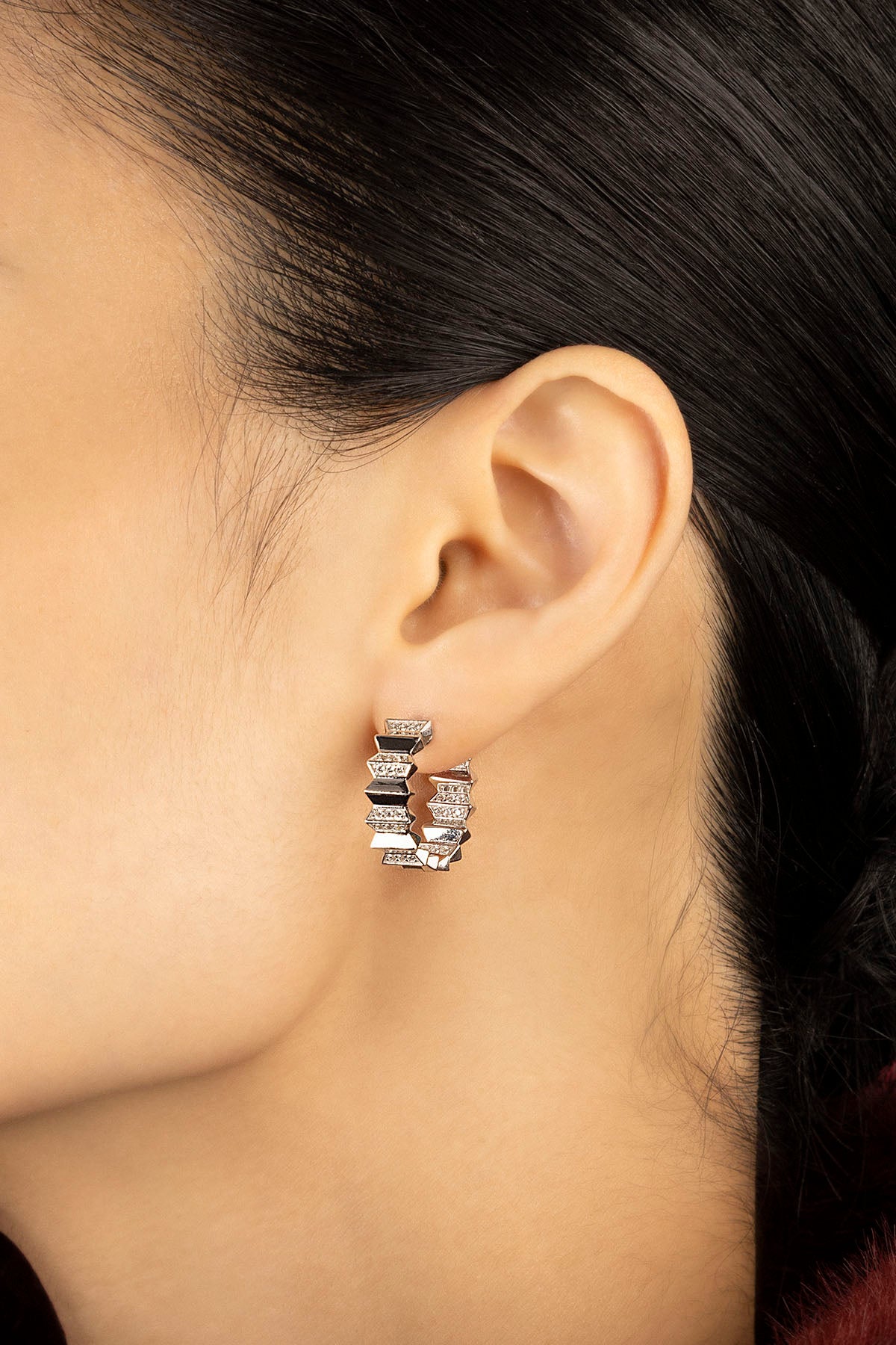 Woman wearing APM Morse Hoop Earrings, a bold rhythm of edges and sparkle.