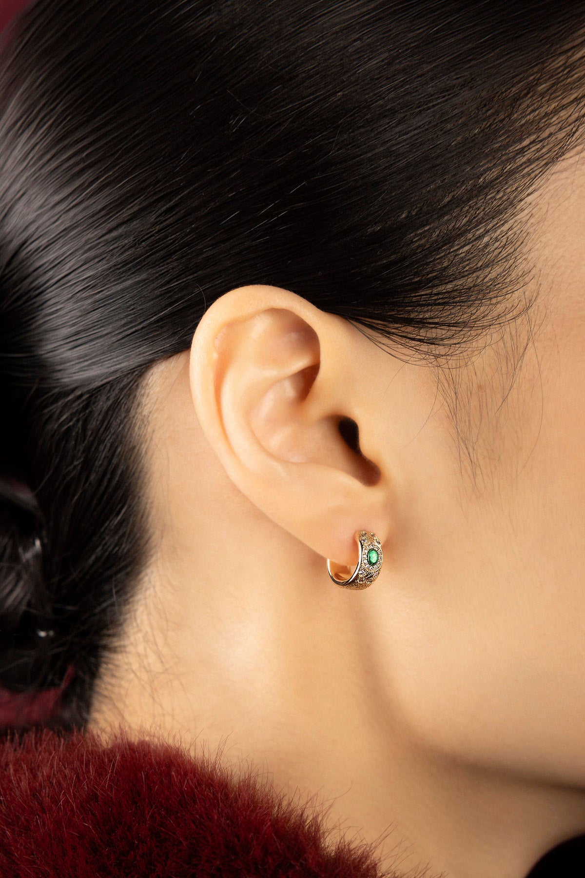 Woman wearing APM hoop earrings, a whisper of green elegance.