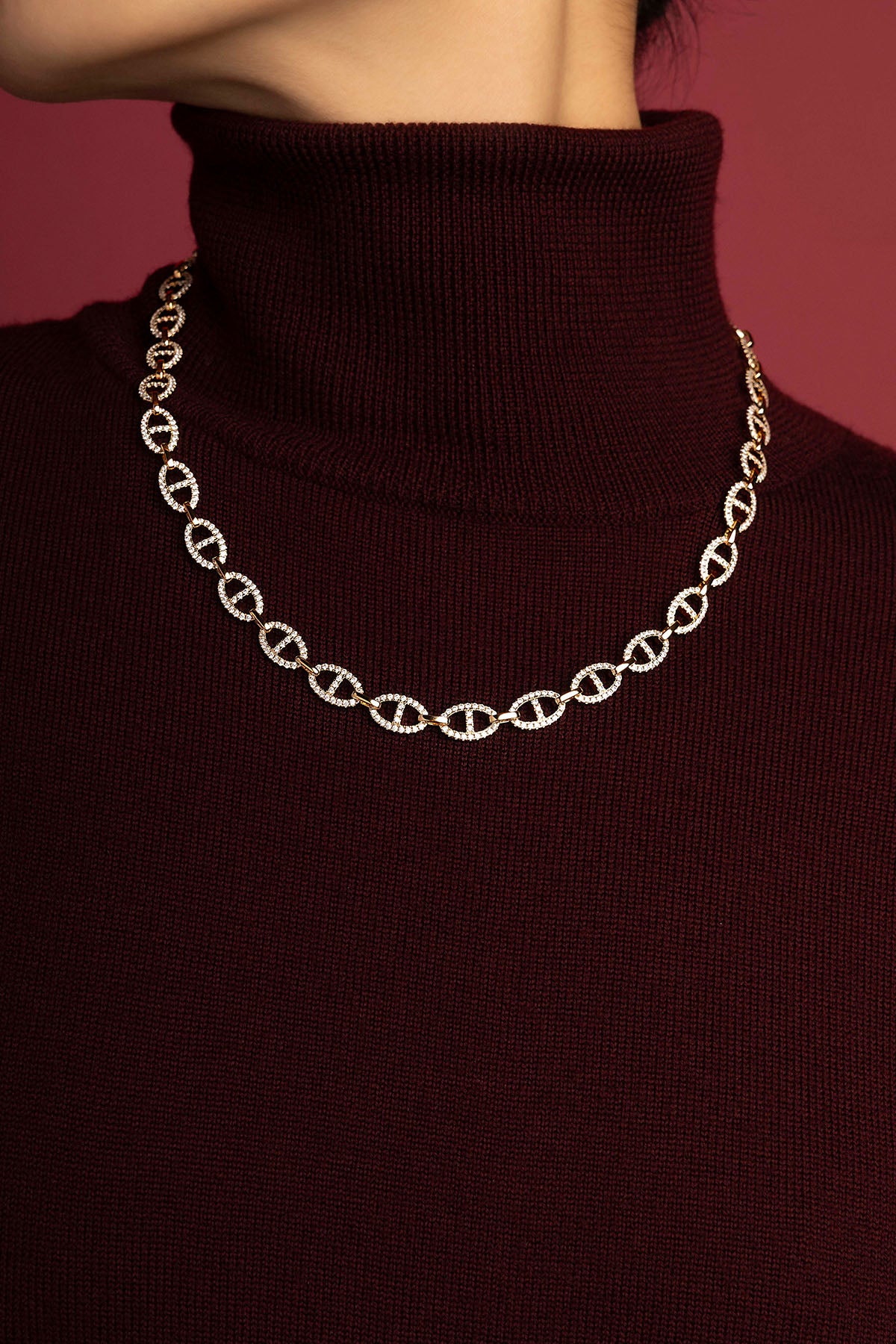 Woman wearing APM Morse Necklace, a shimmering statement over cozy burgundy knit.