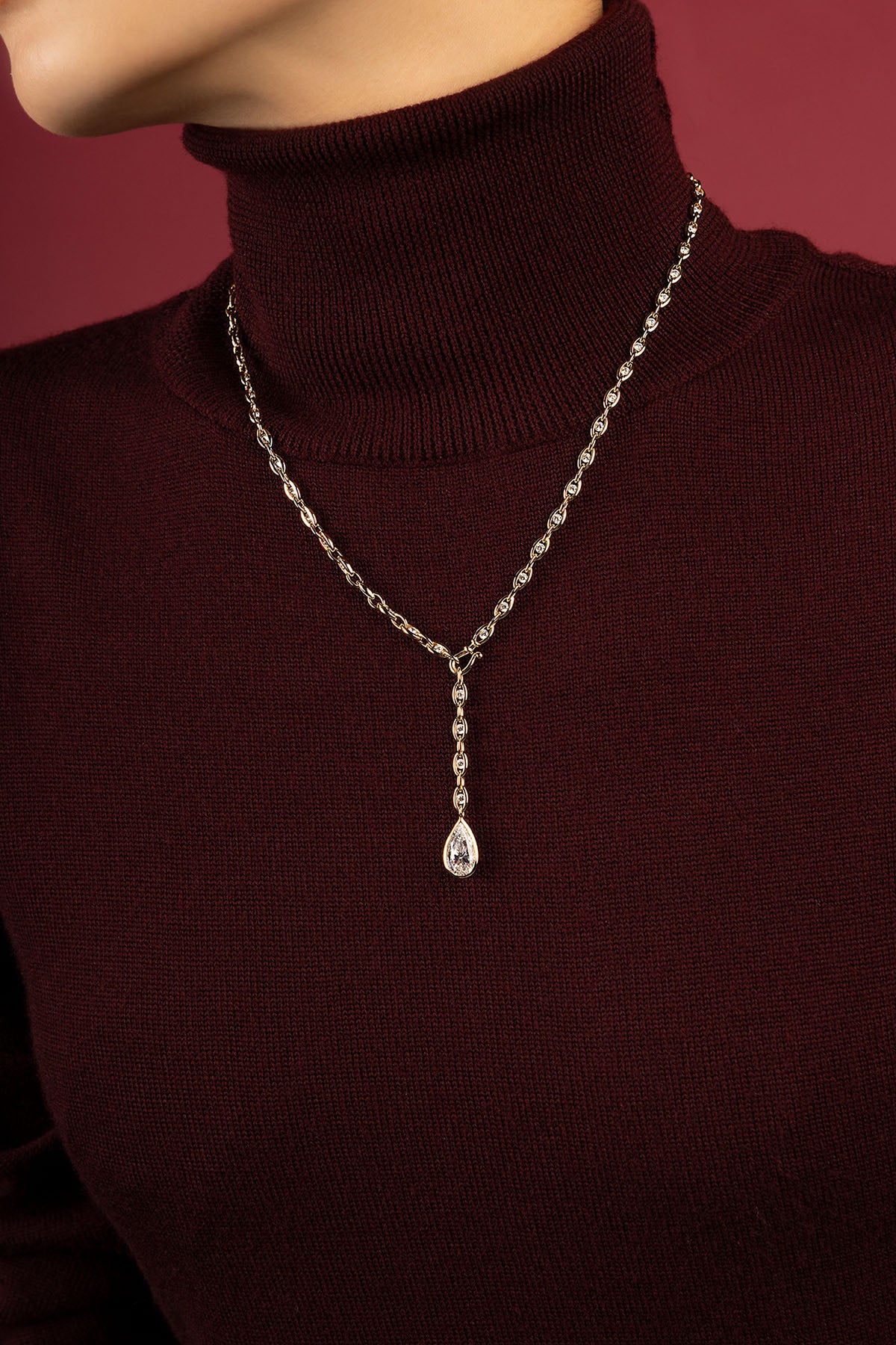 Woman wearing APM necklace, a teardrop pendant falling with quiet elegance.