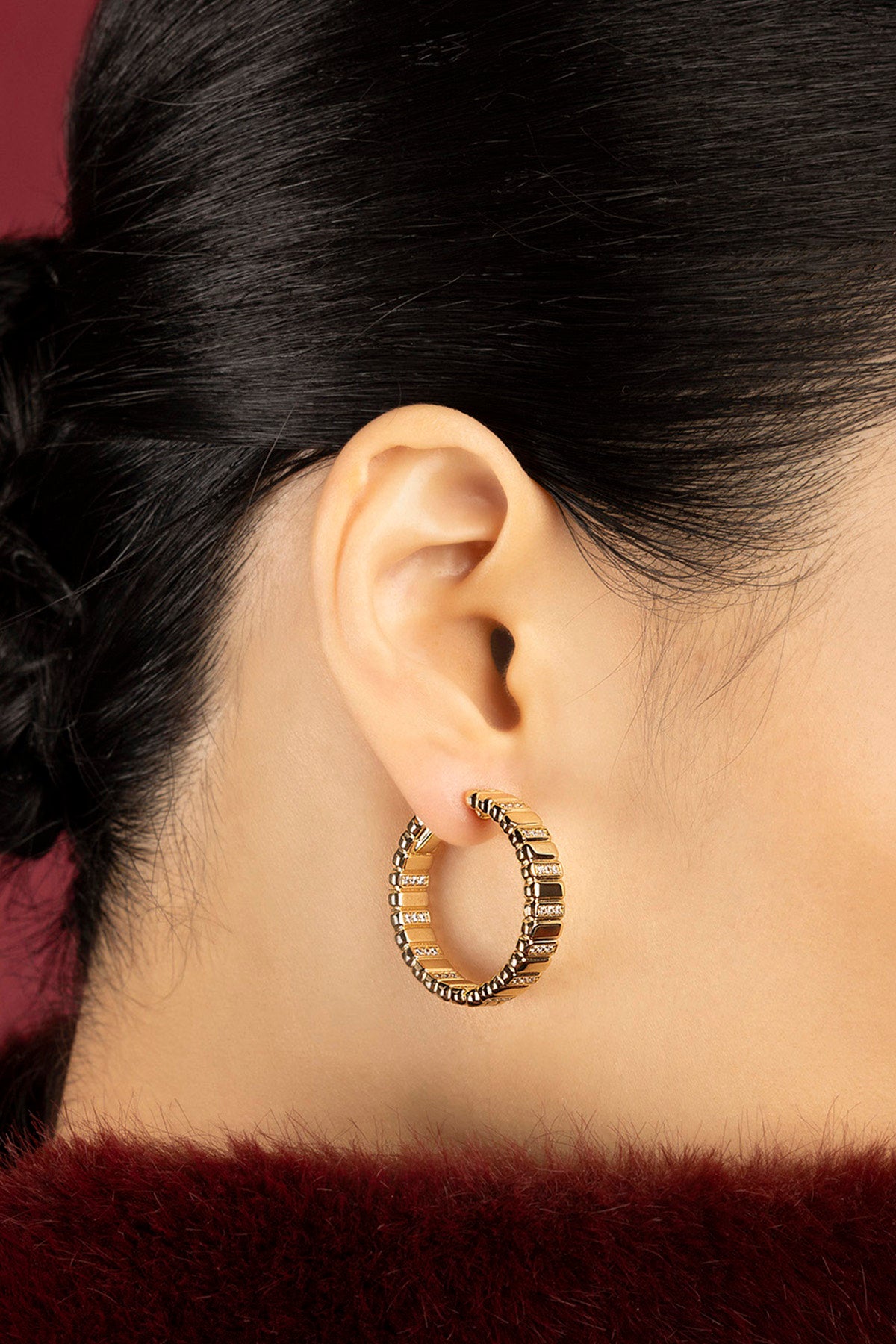 Woman wearing APM Hoop Earrings, a golden statement of quiet confidence.