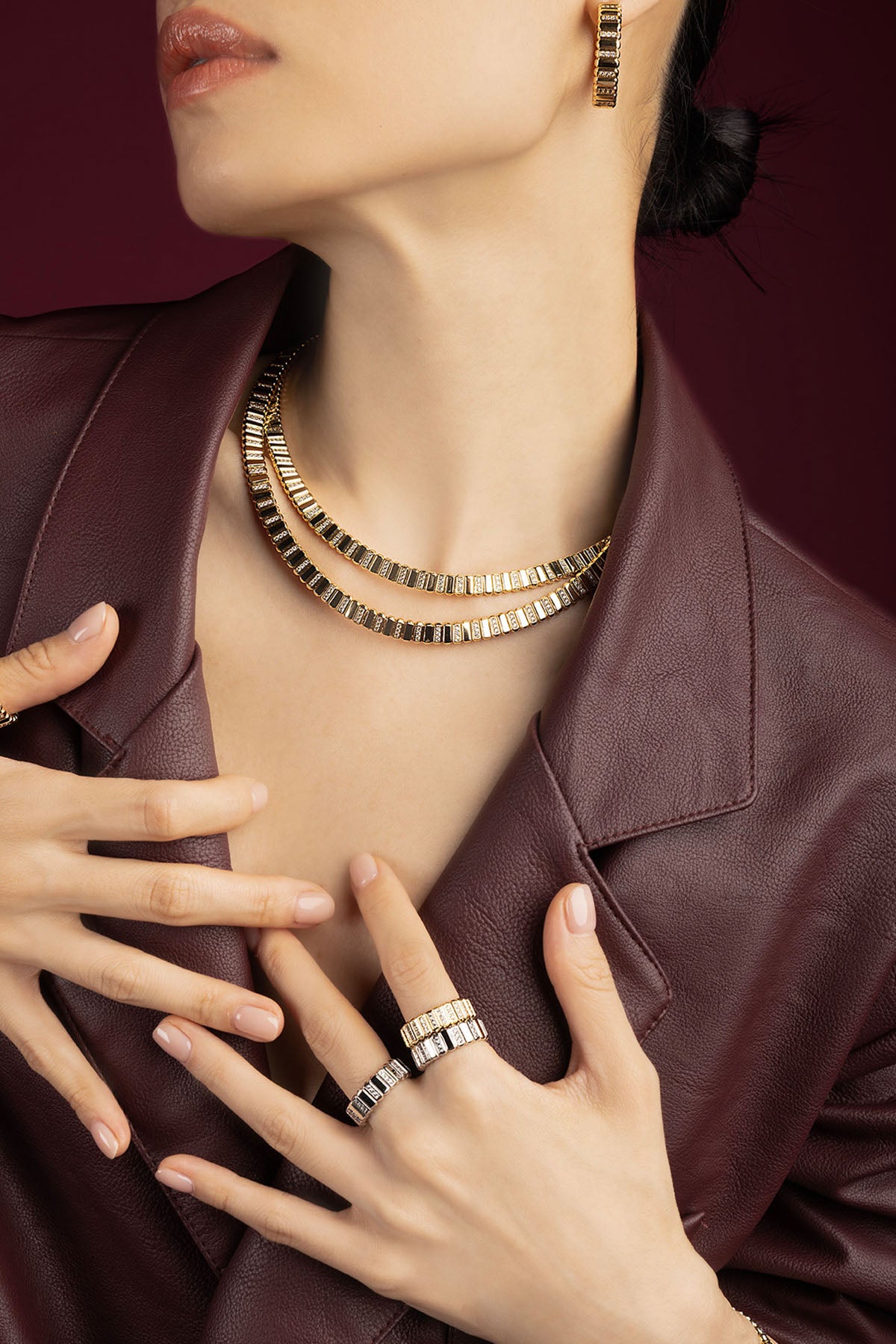 Woman wearing APM Monaco layered necklaces, rings and earrings, radiant in golden sophistication.