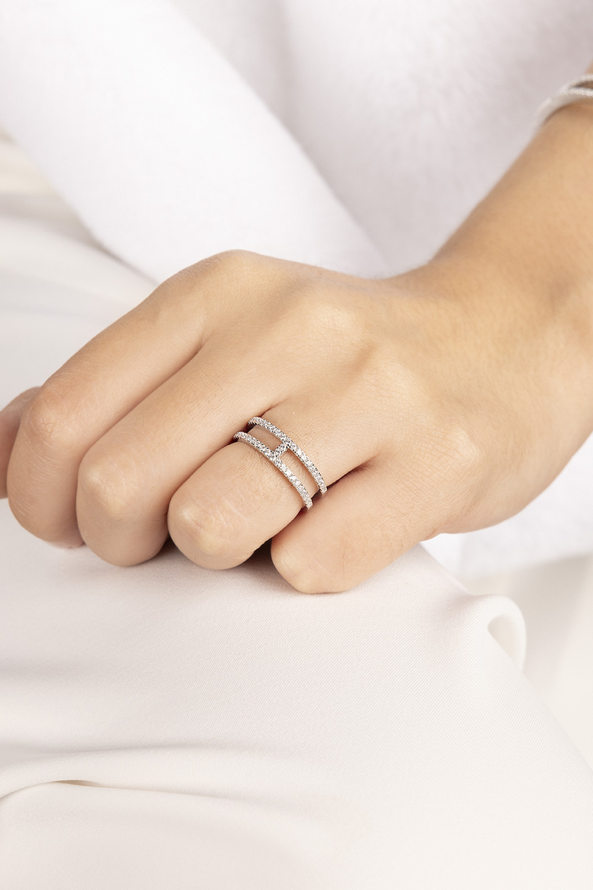 Close-up of a hand wearing APM MONACO silver ring with double-line design on a white background